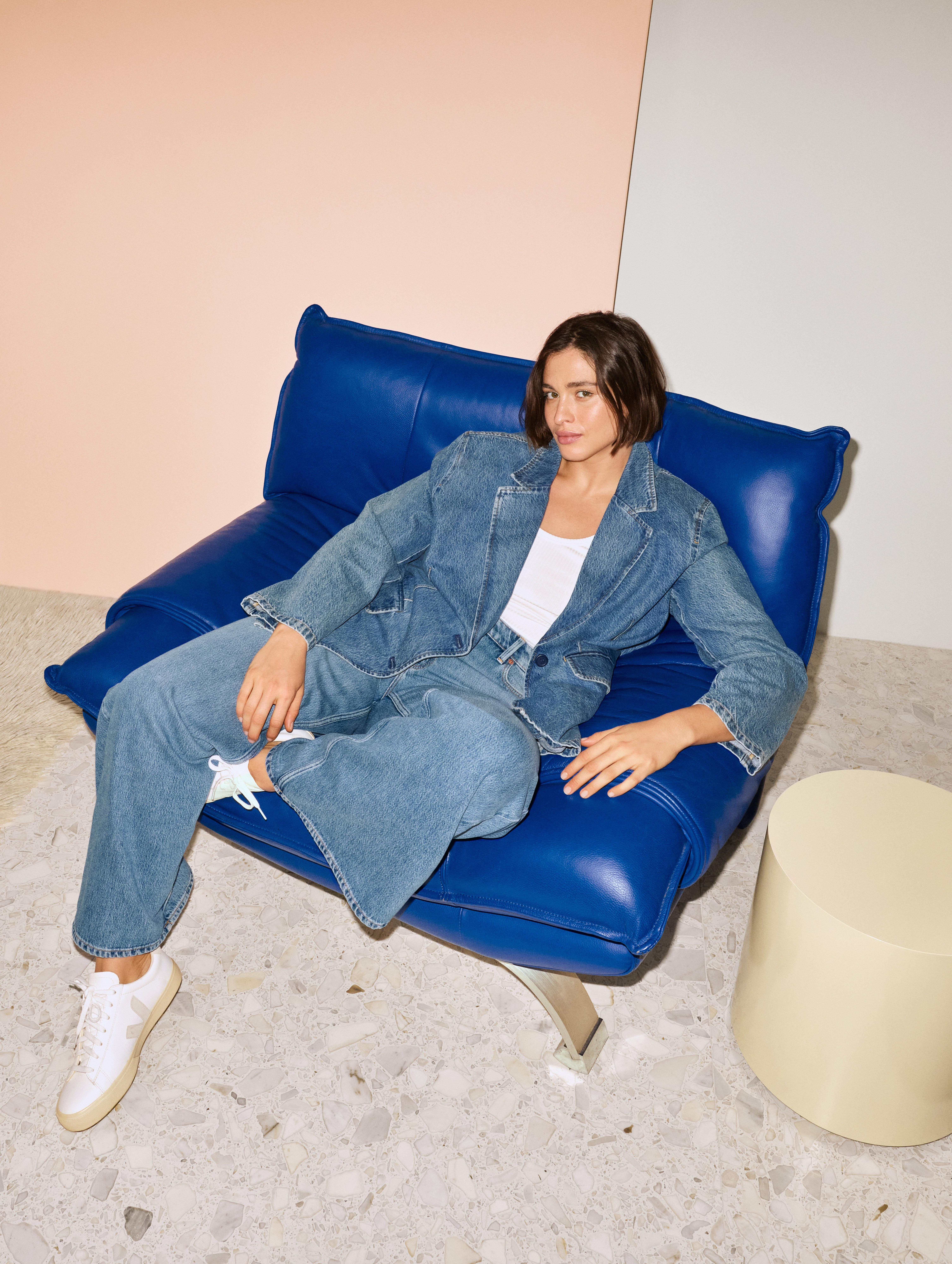 A woman wearing Lindex jeans sitting in a blue chair.