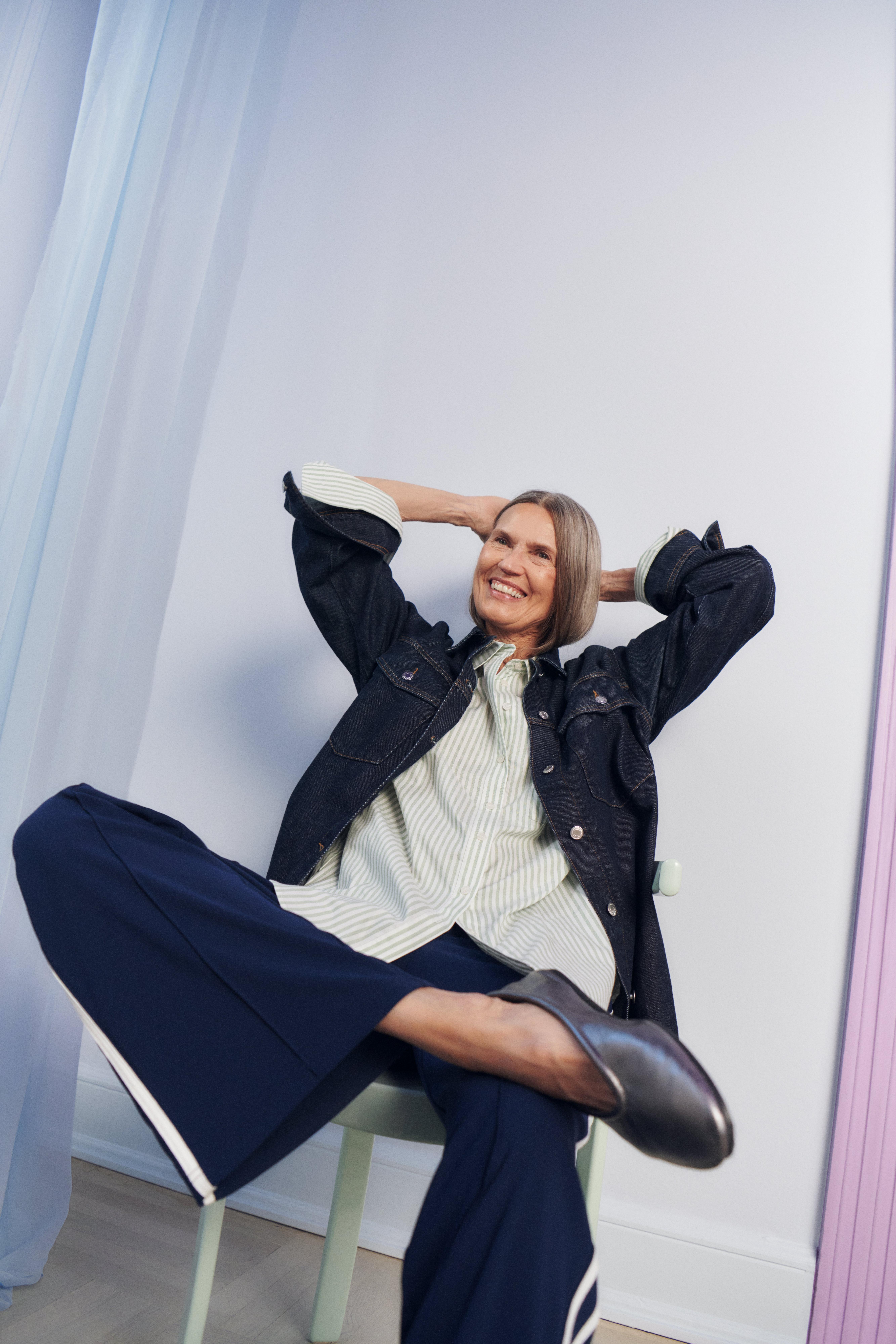 A woman sitting on a chair wearing checkered pants.