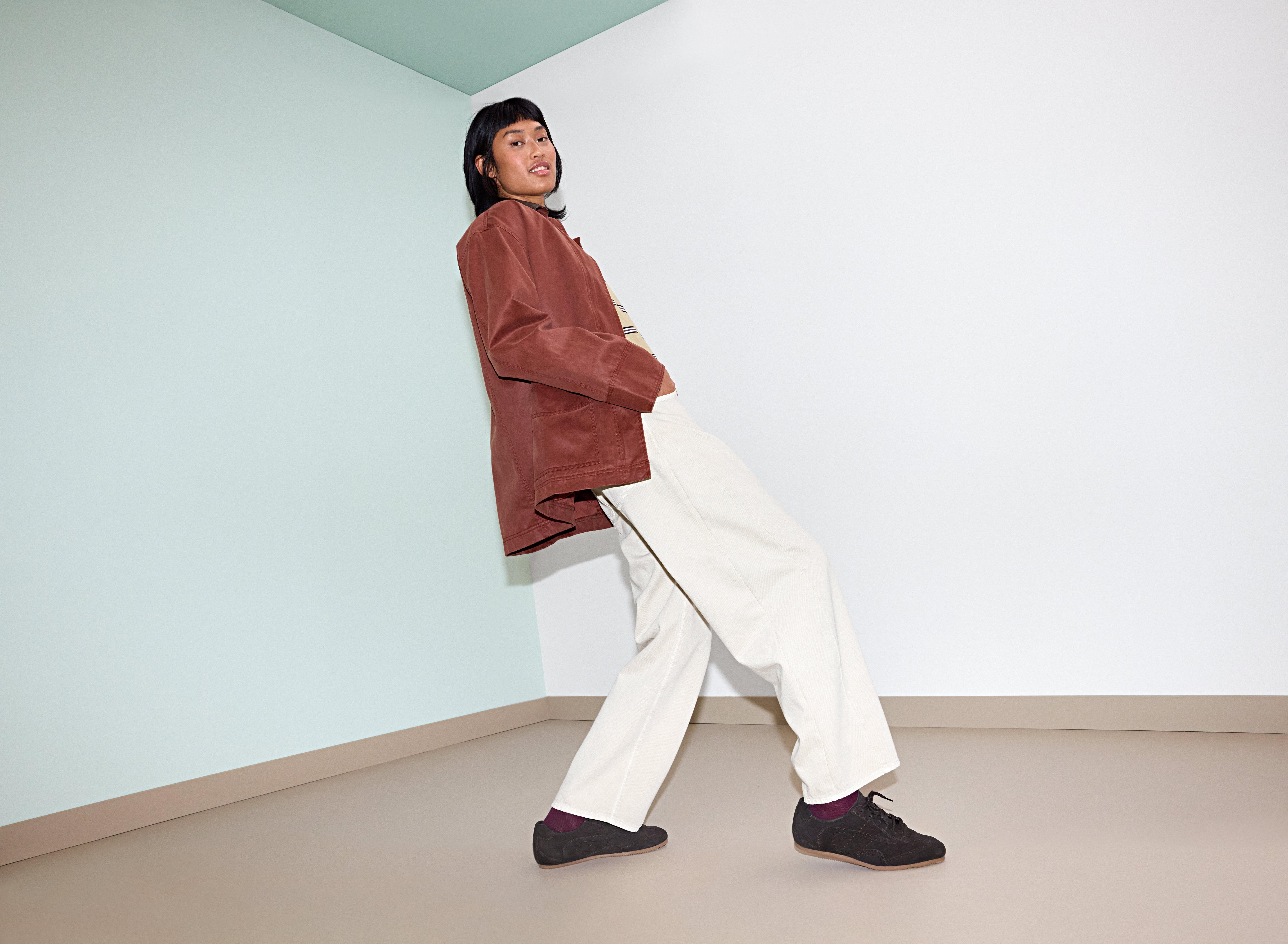 Kvinna i brun jacka och vita byxor