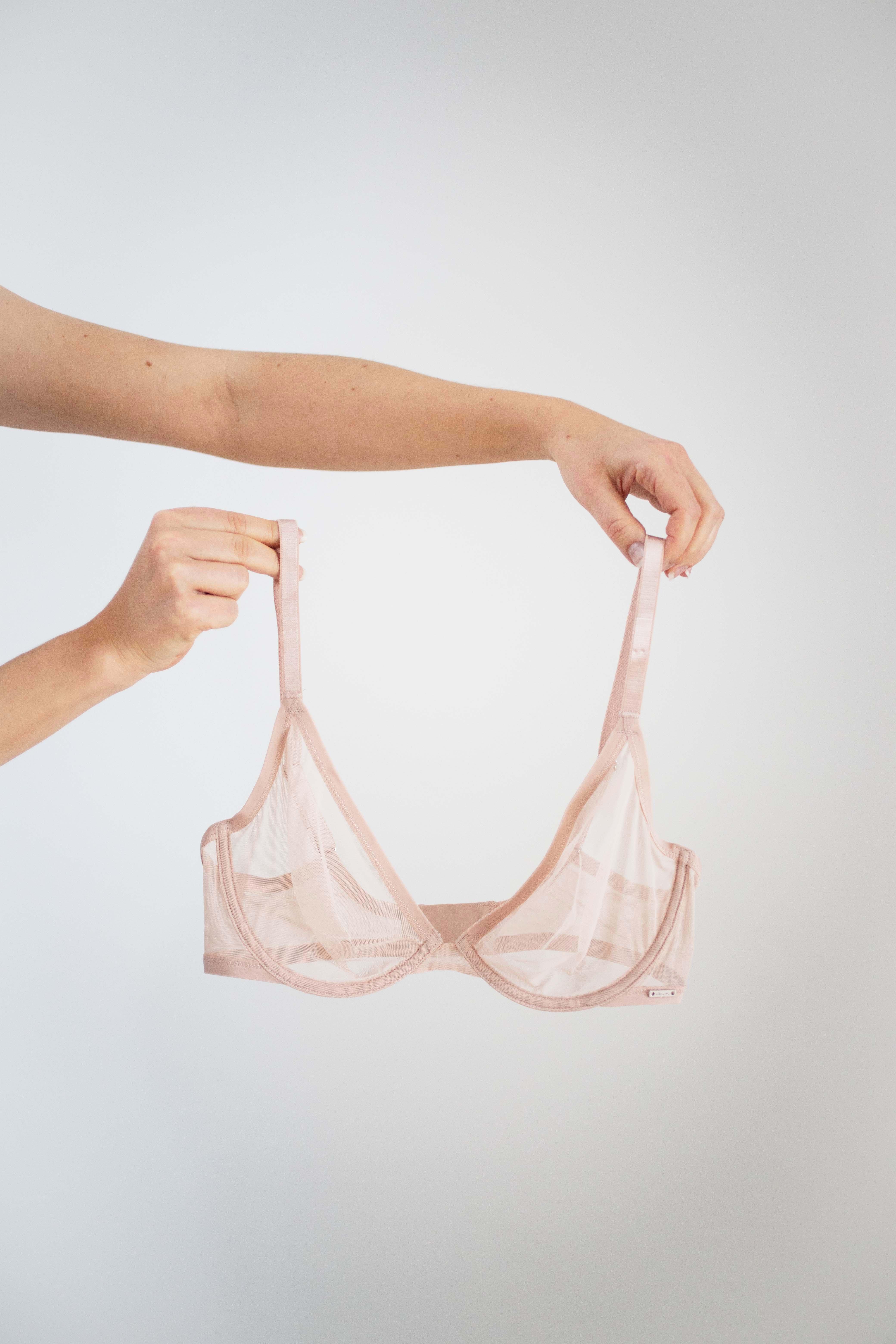 Ett par händer som håller i en bh i skirt material.