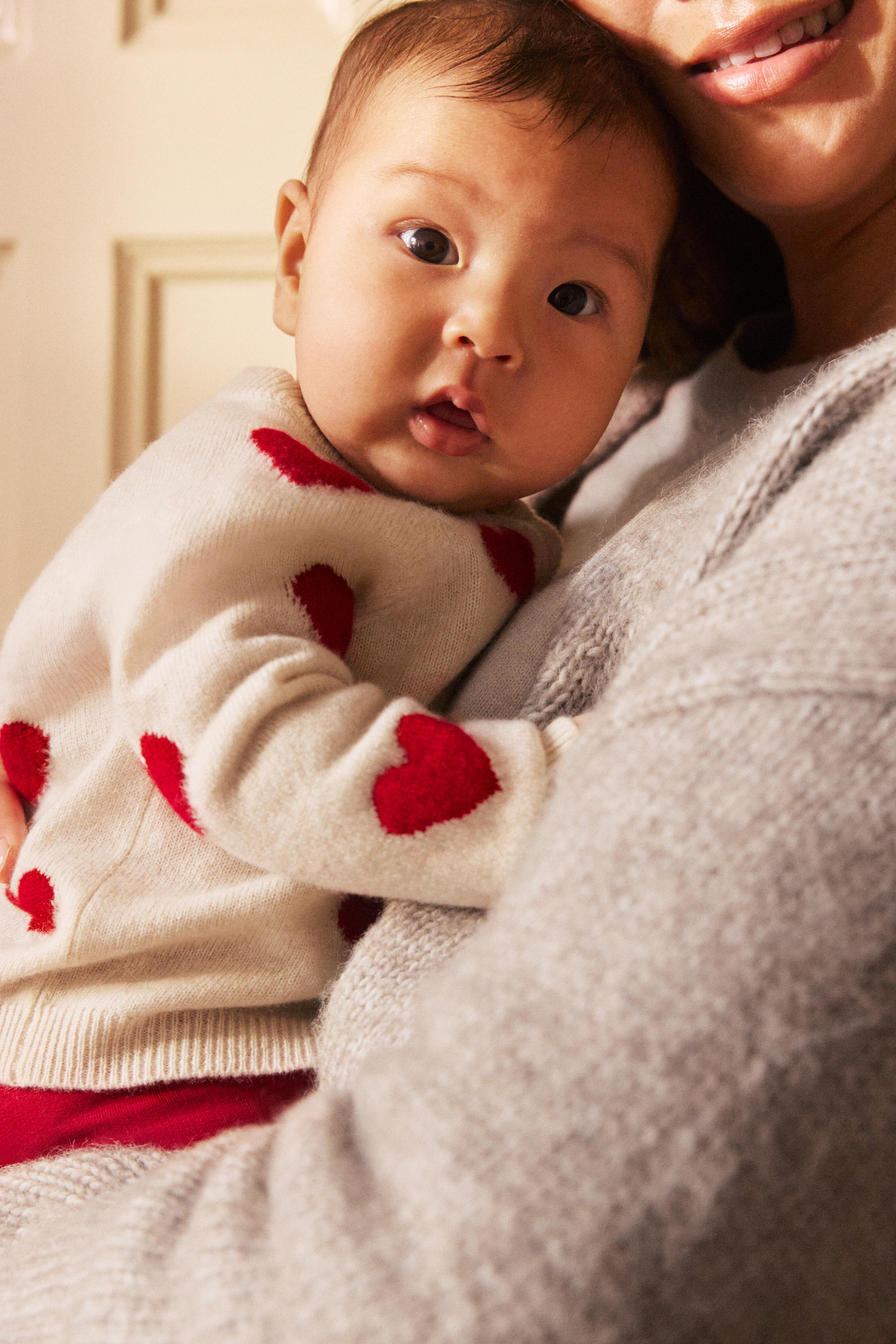Close-up on a baby in a cardigan with hearts.