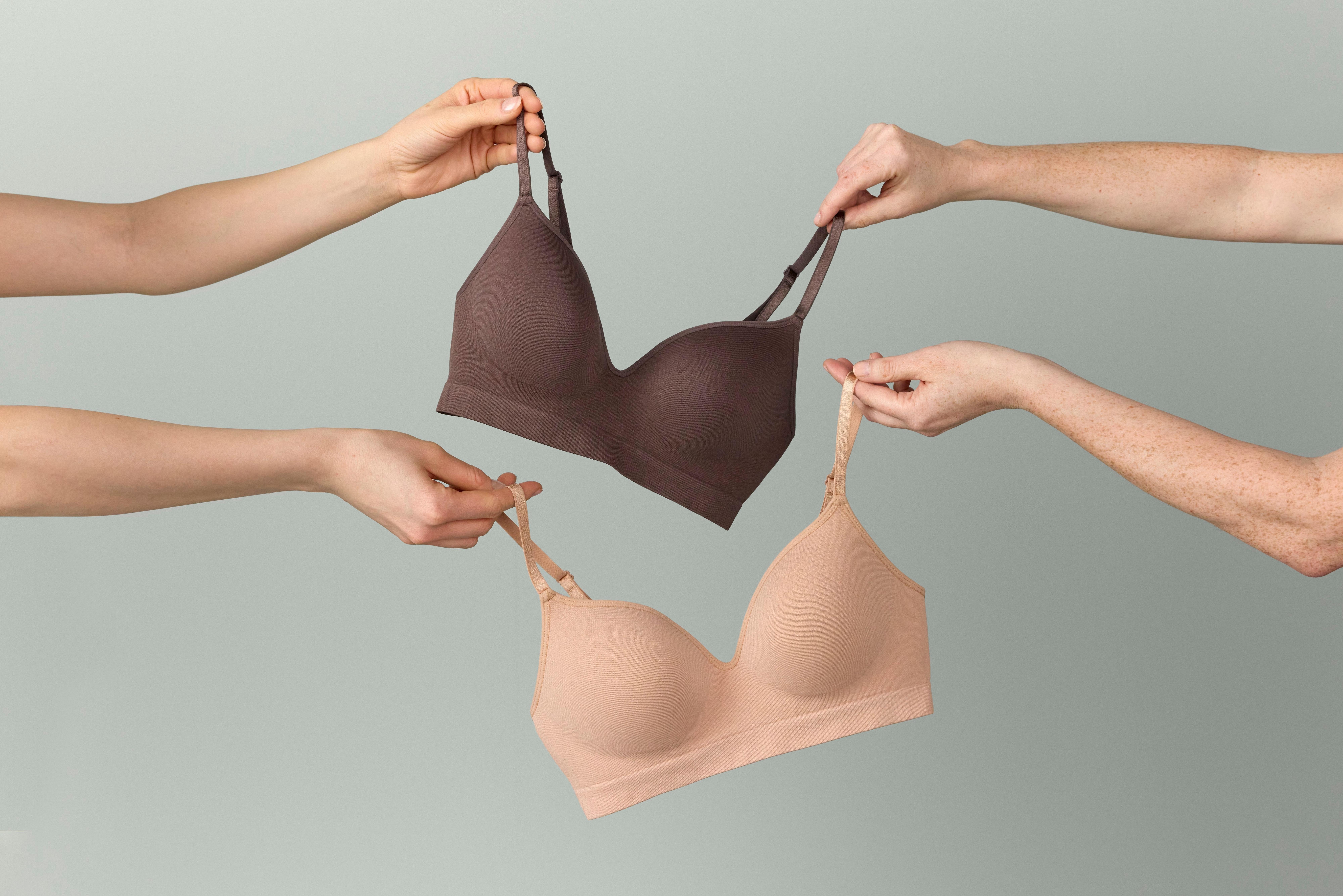 Two hands holding two bras one dark and one beige from Lindex.