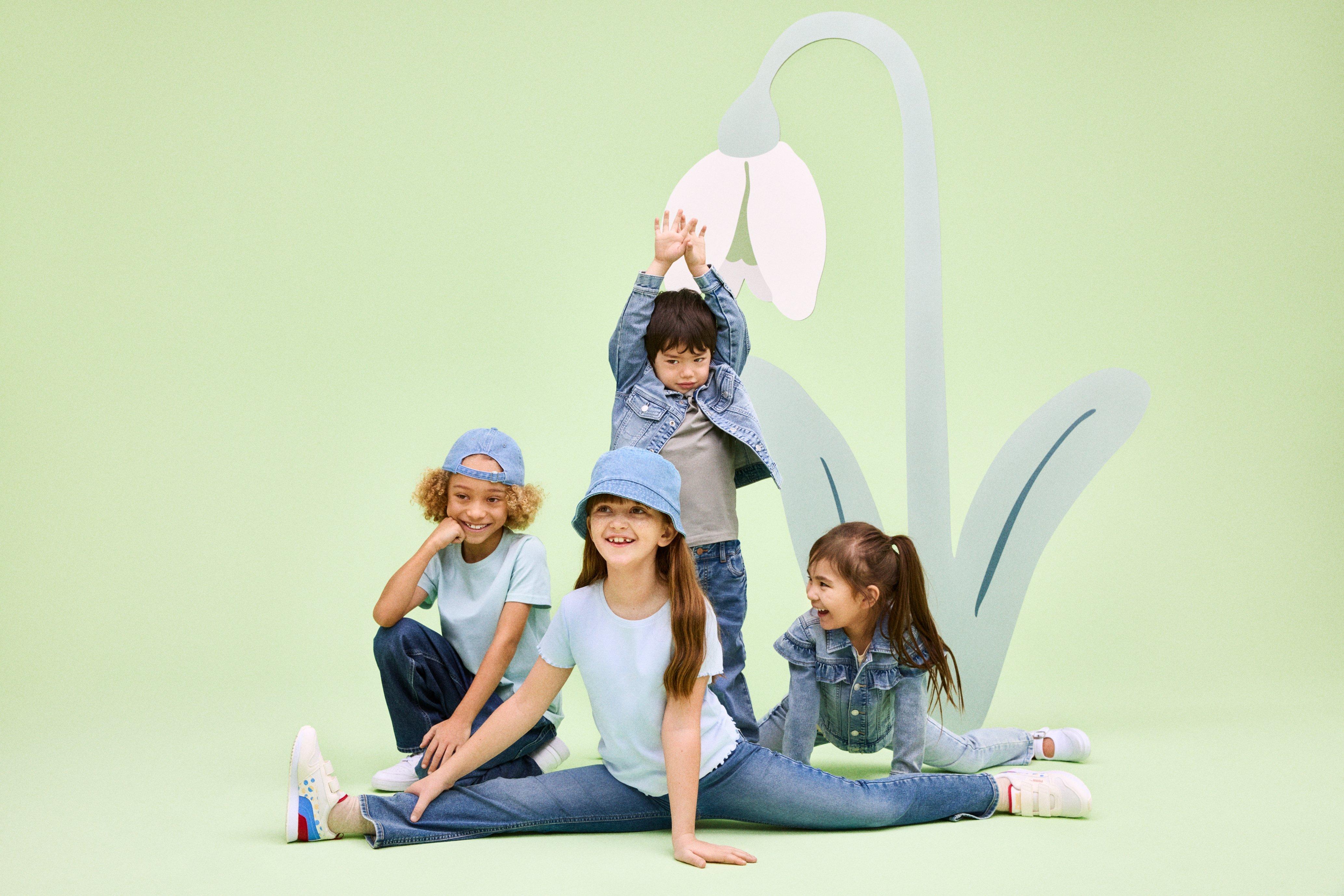Four children dressed in jeans from Lindex jumping around and playing.