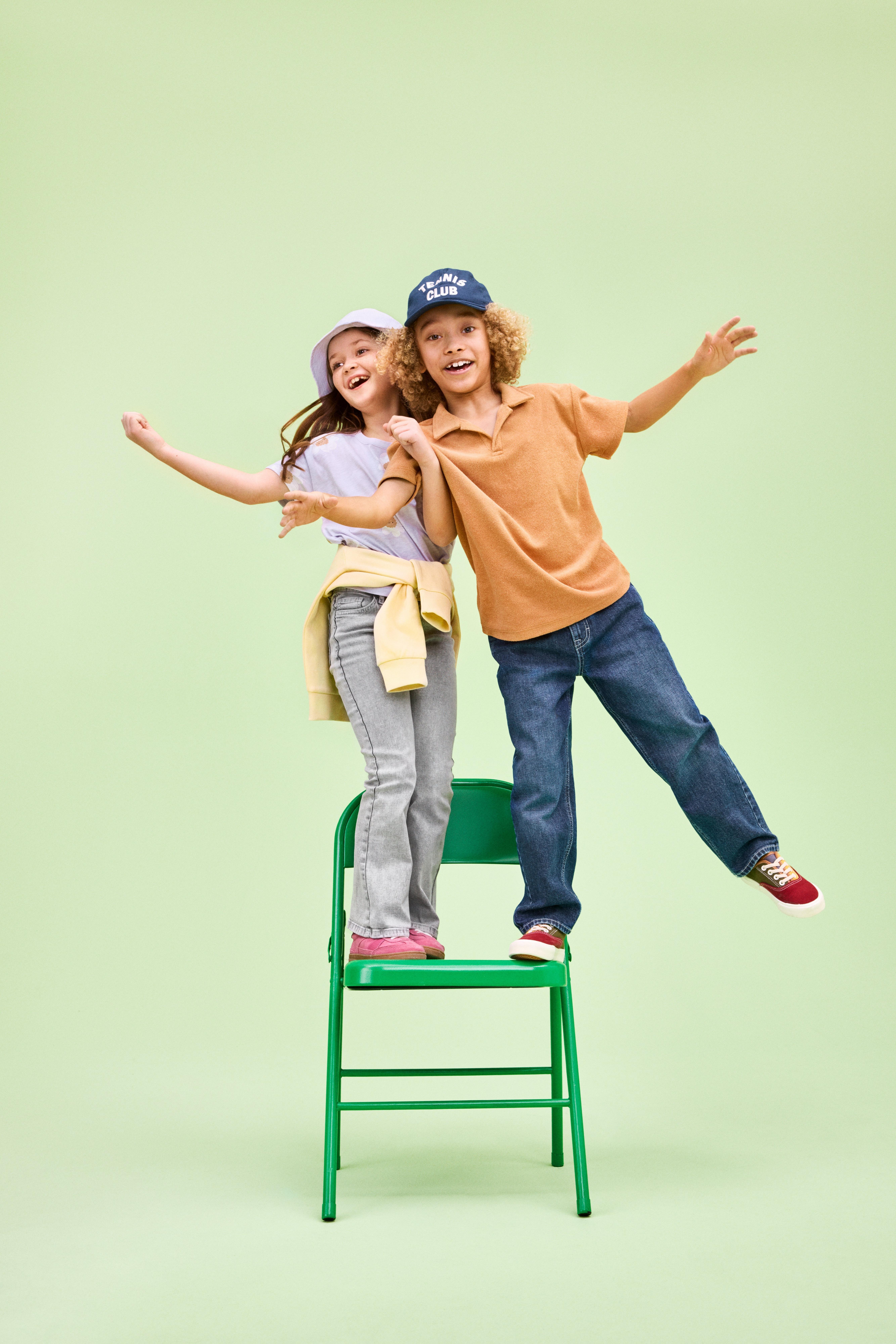 Two kids standing on a blue chair.