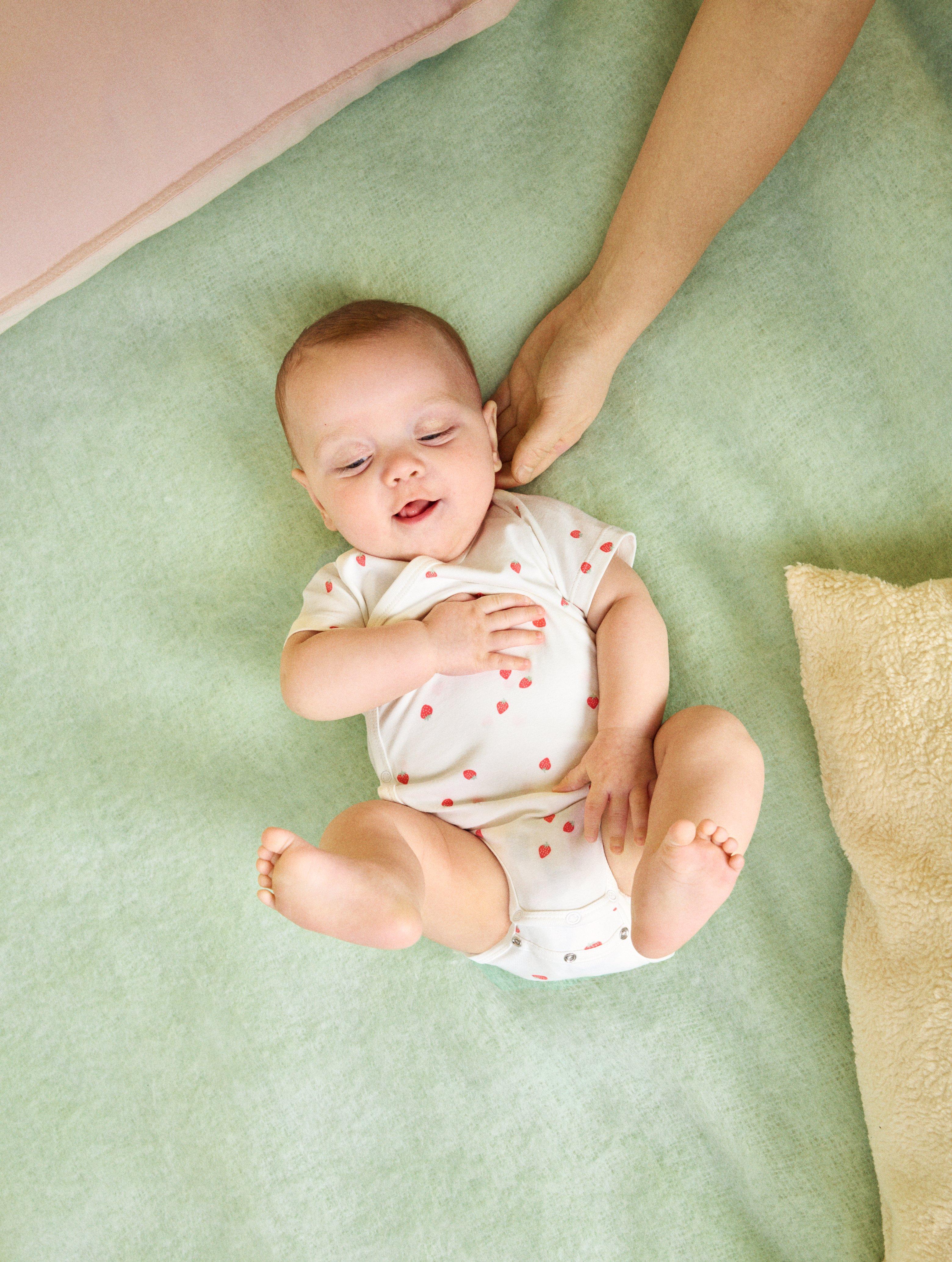 En bebis som bär en kropp i trendig storlek med knappar i skrevet.