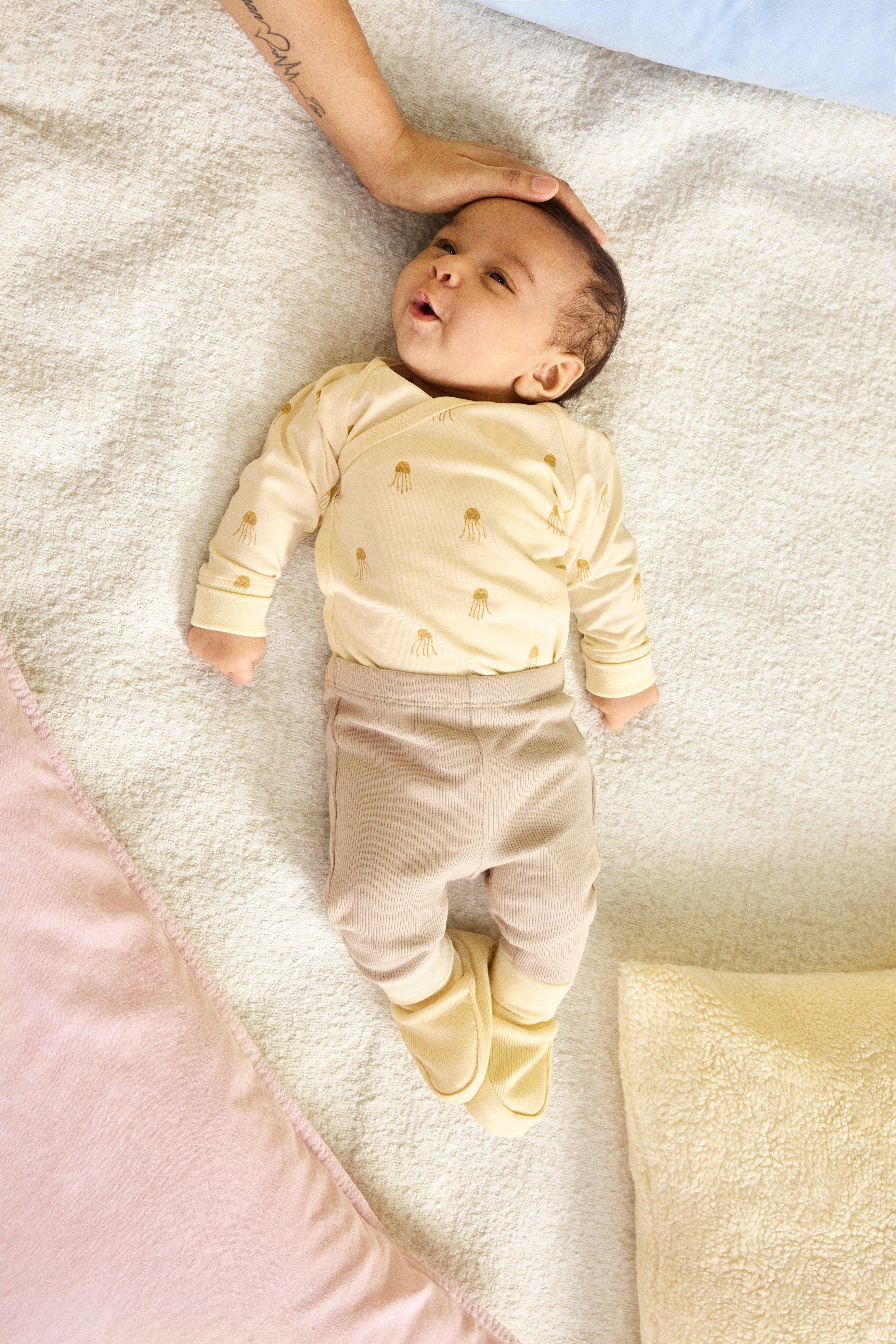 Baby lying on a yellow cosy blanket wearing a Lindex starter kit.