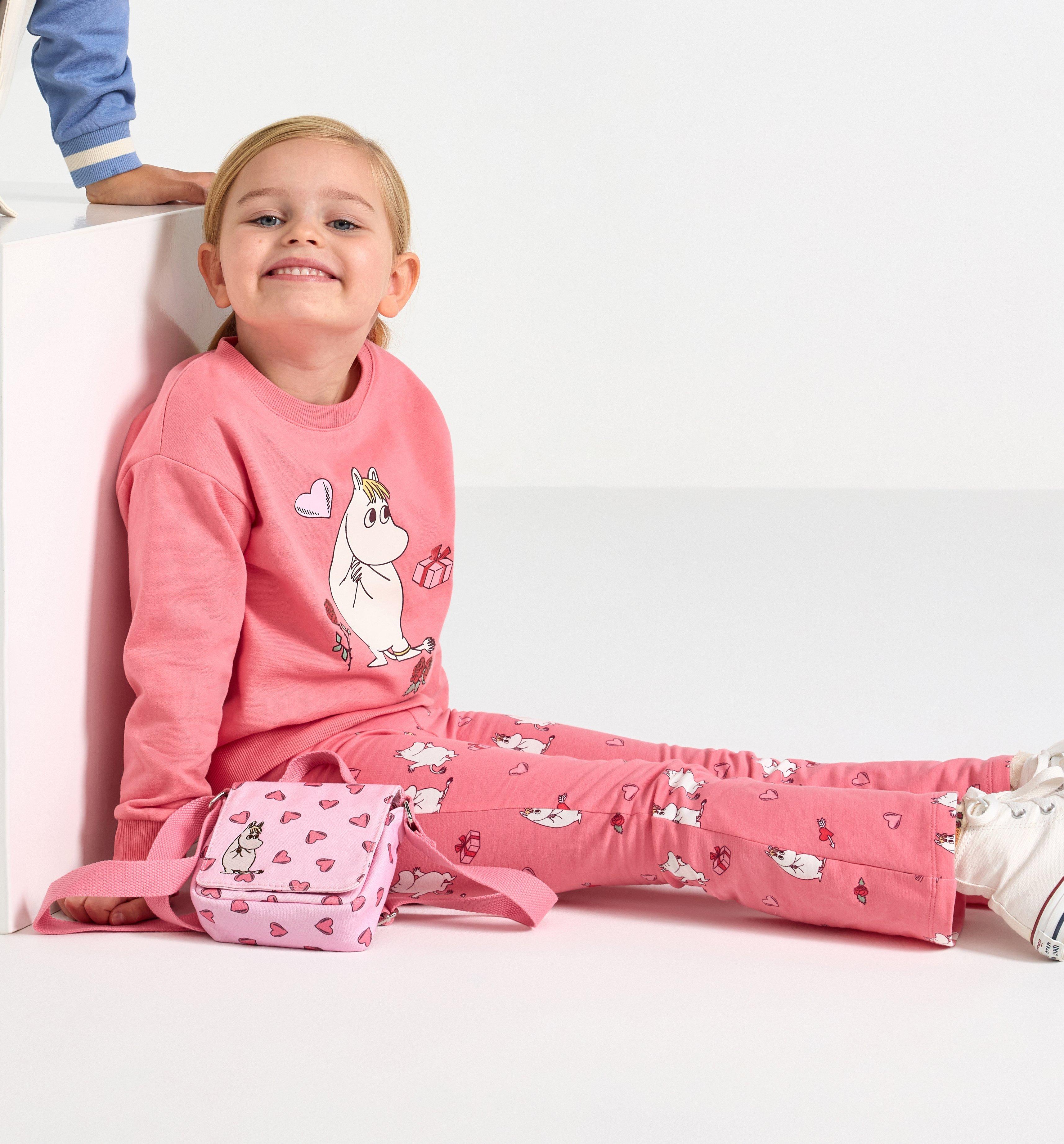 A girl dressed in a pink jumper with Moomin print.