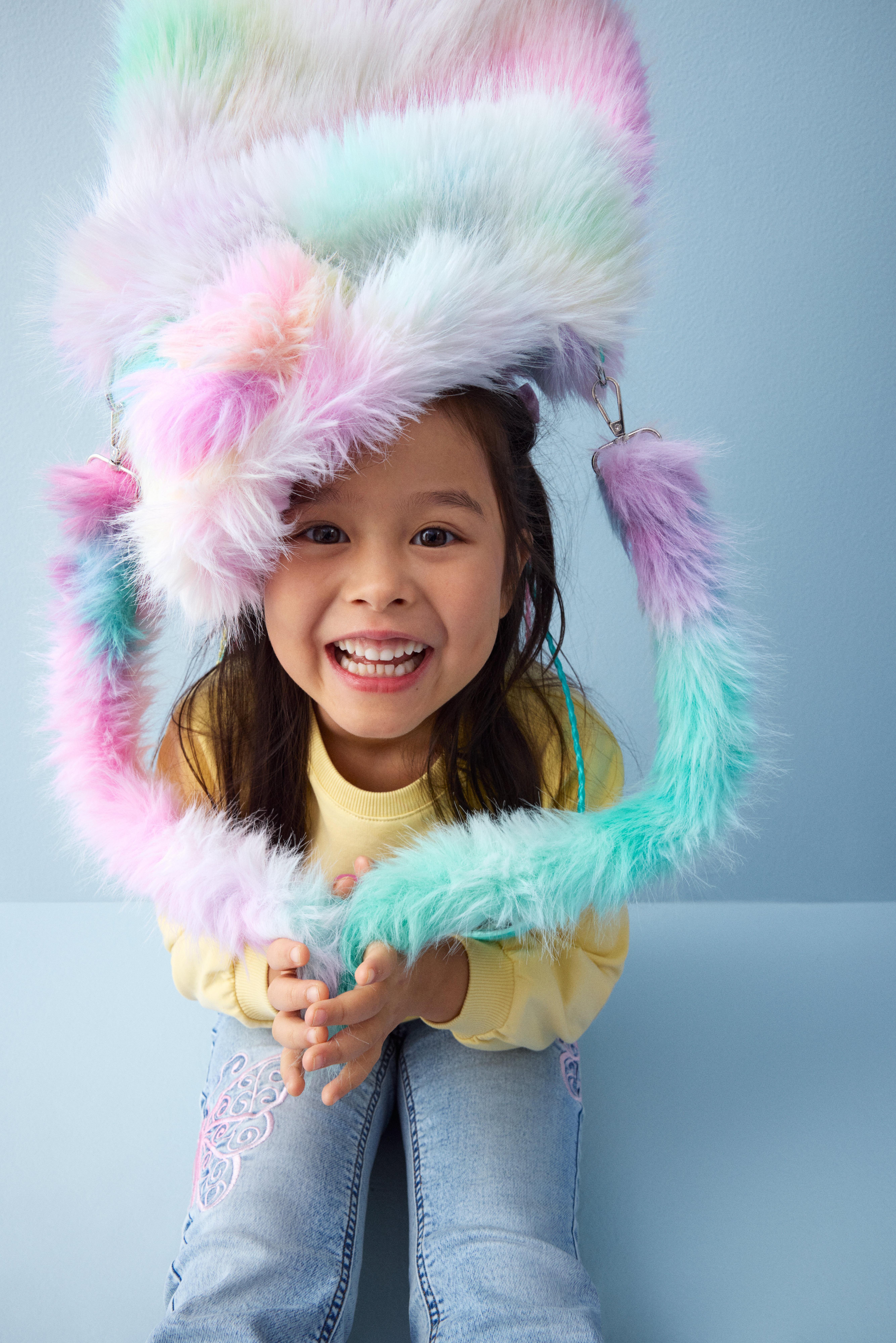 Bild på en leende Alba, hon håller en fluffig regnbågsväska över huvudet.