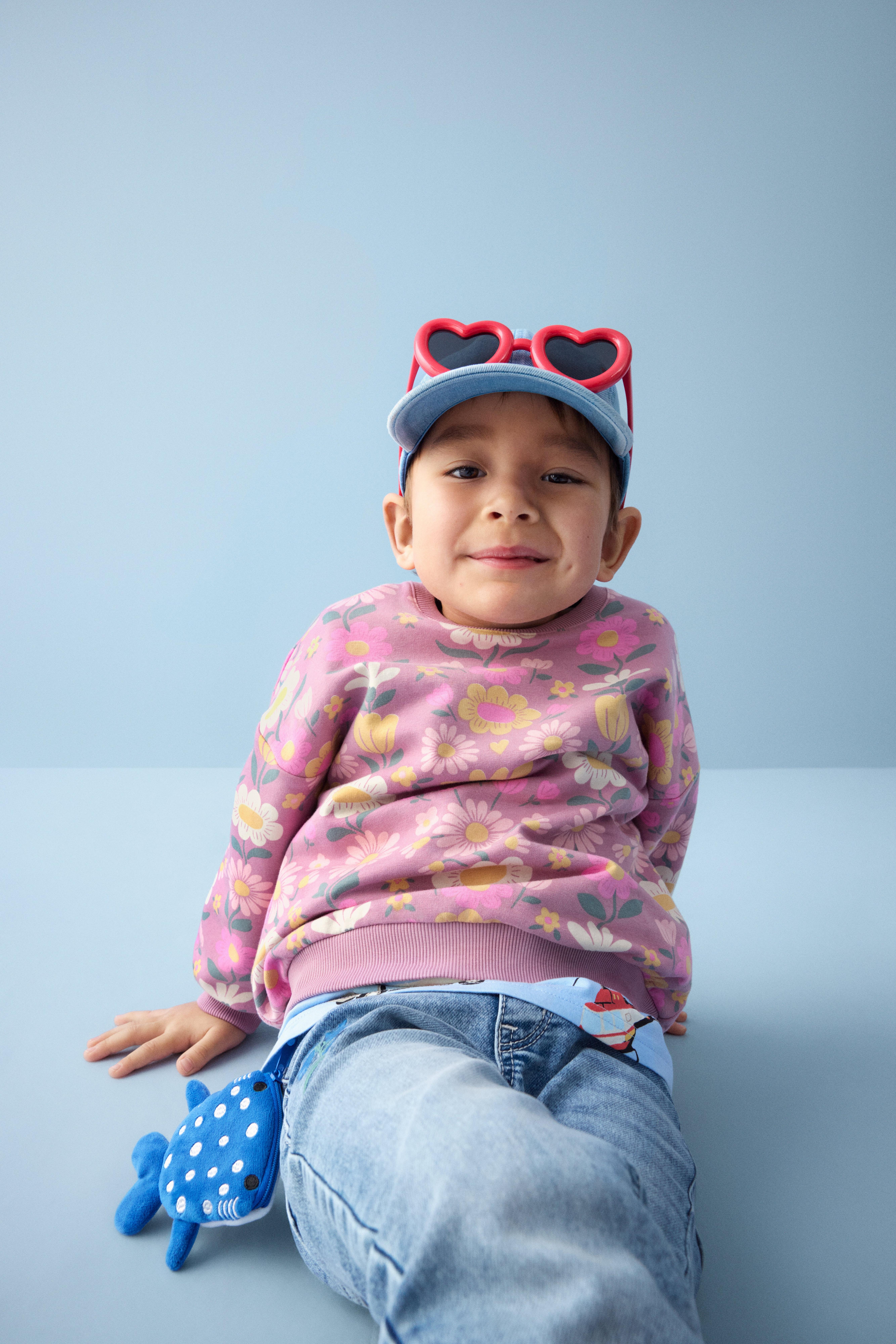 Bild på Otis, klädd i en jumper med blommor och jeans.