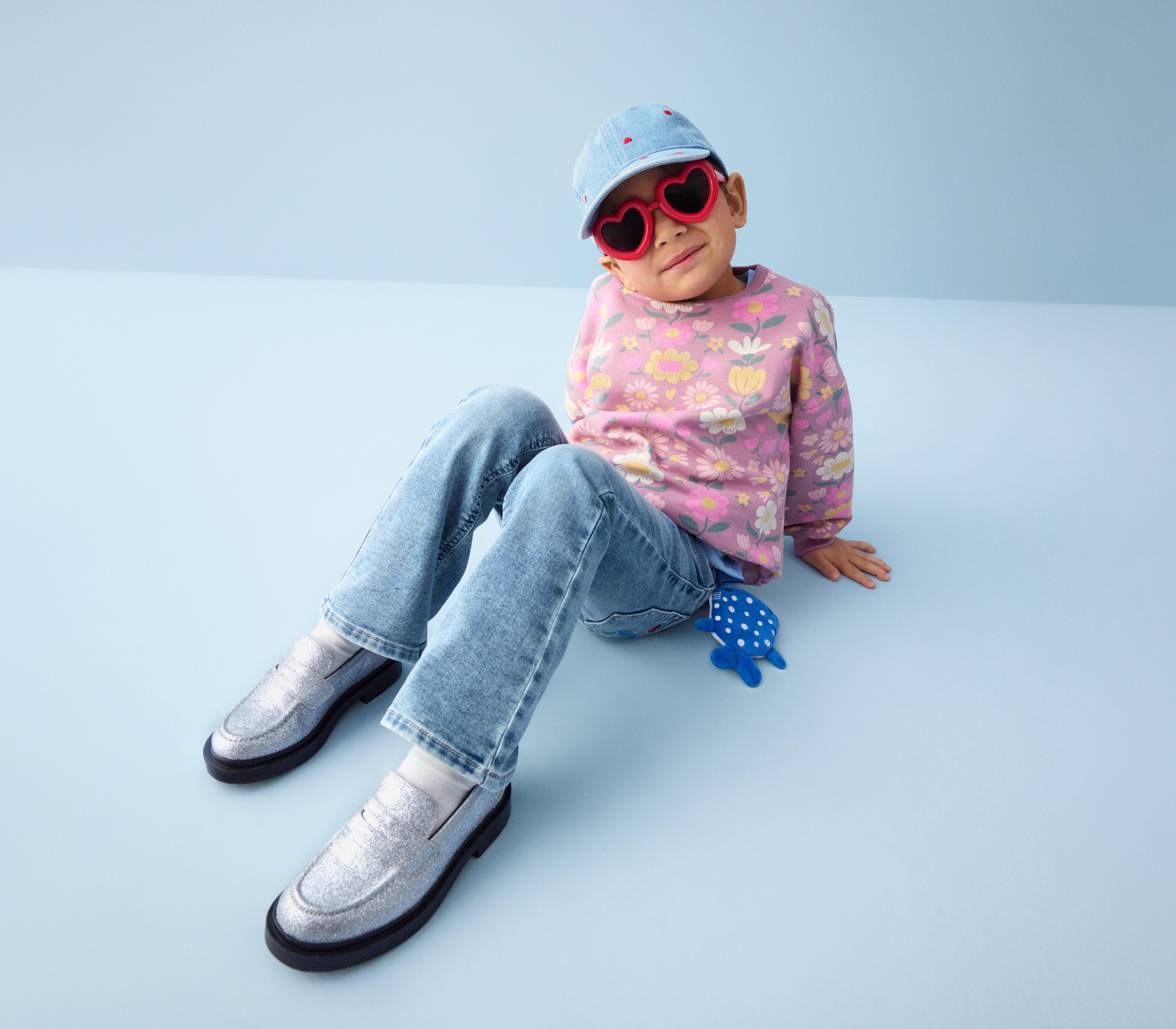 En leende Malcom klädd i en beige trenchcoat som tittar in i kameran.