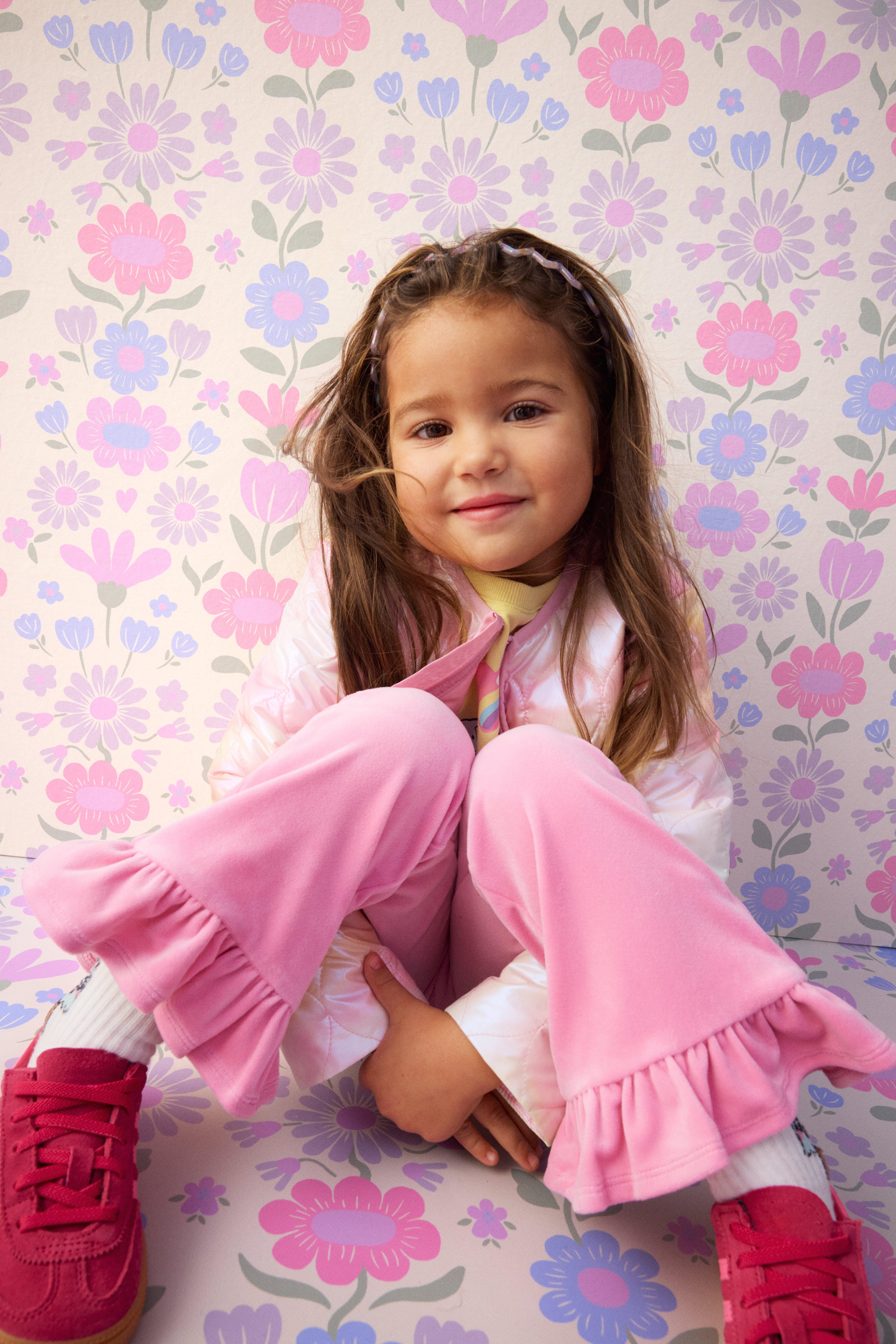 A girl agains a flower pattern.