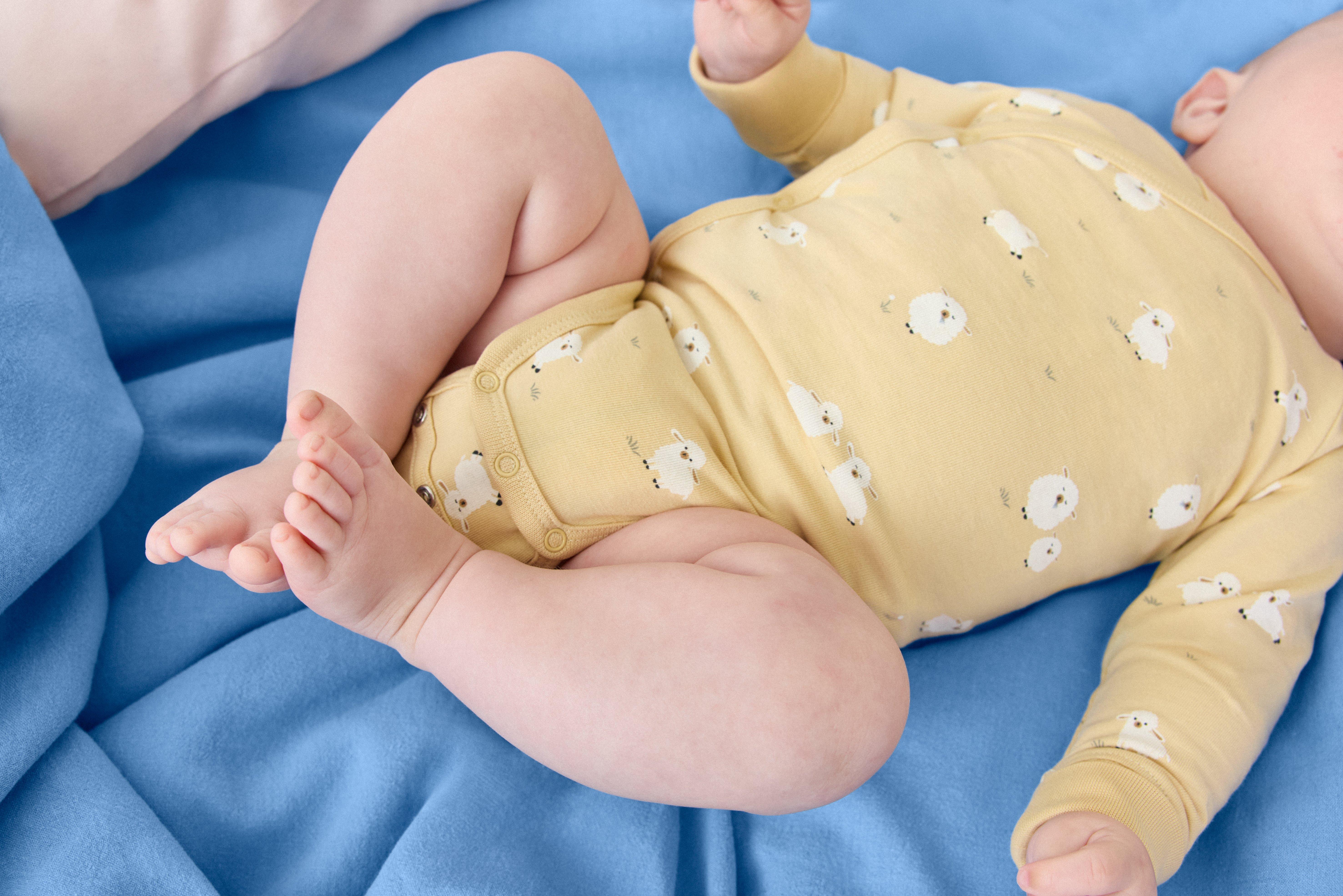A baby wearing an extrended size body with buttons in the crotch.