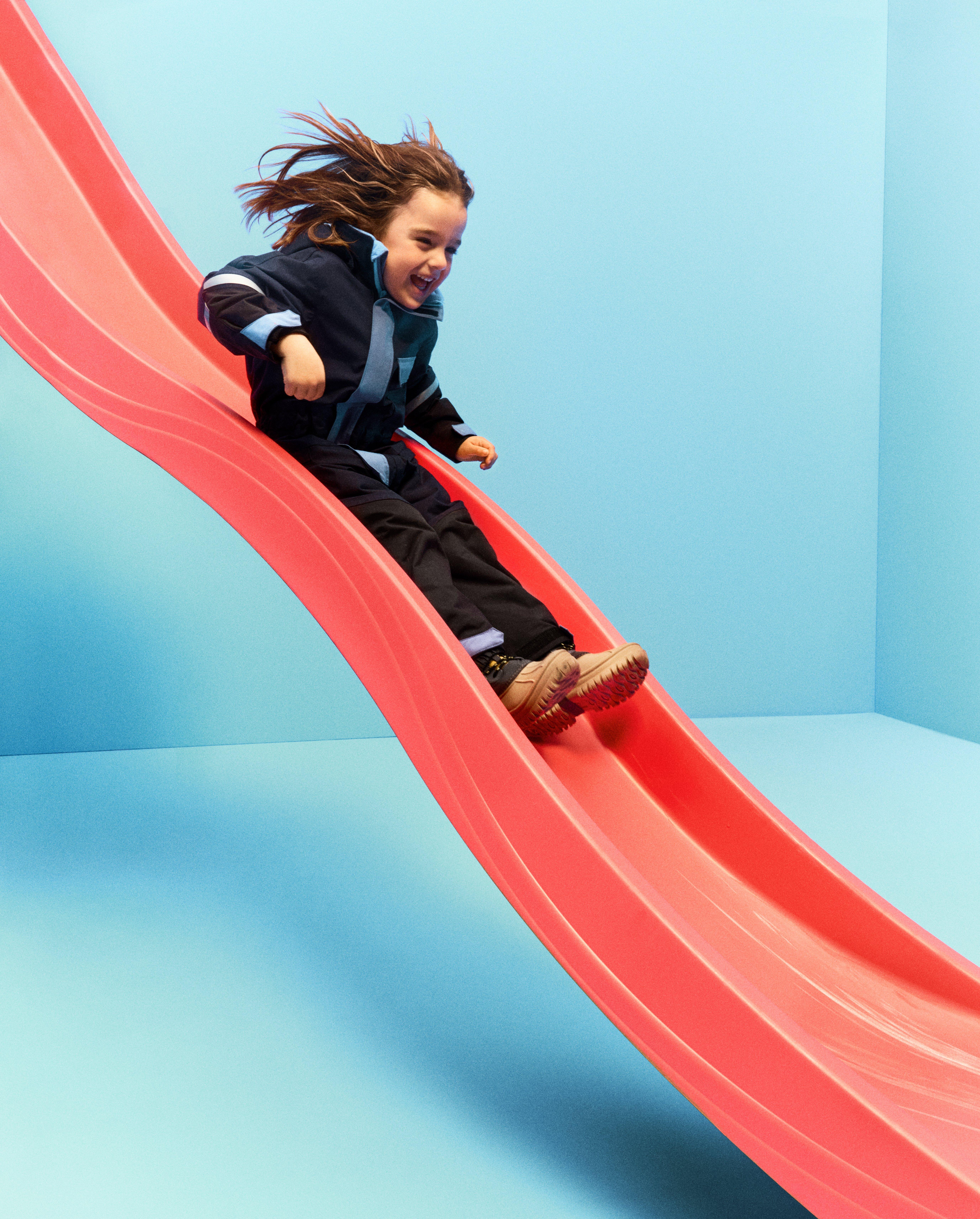 Ett barn i slitstarka kläder från Lindex åker rutschkana