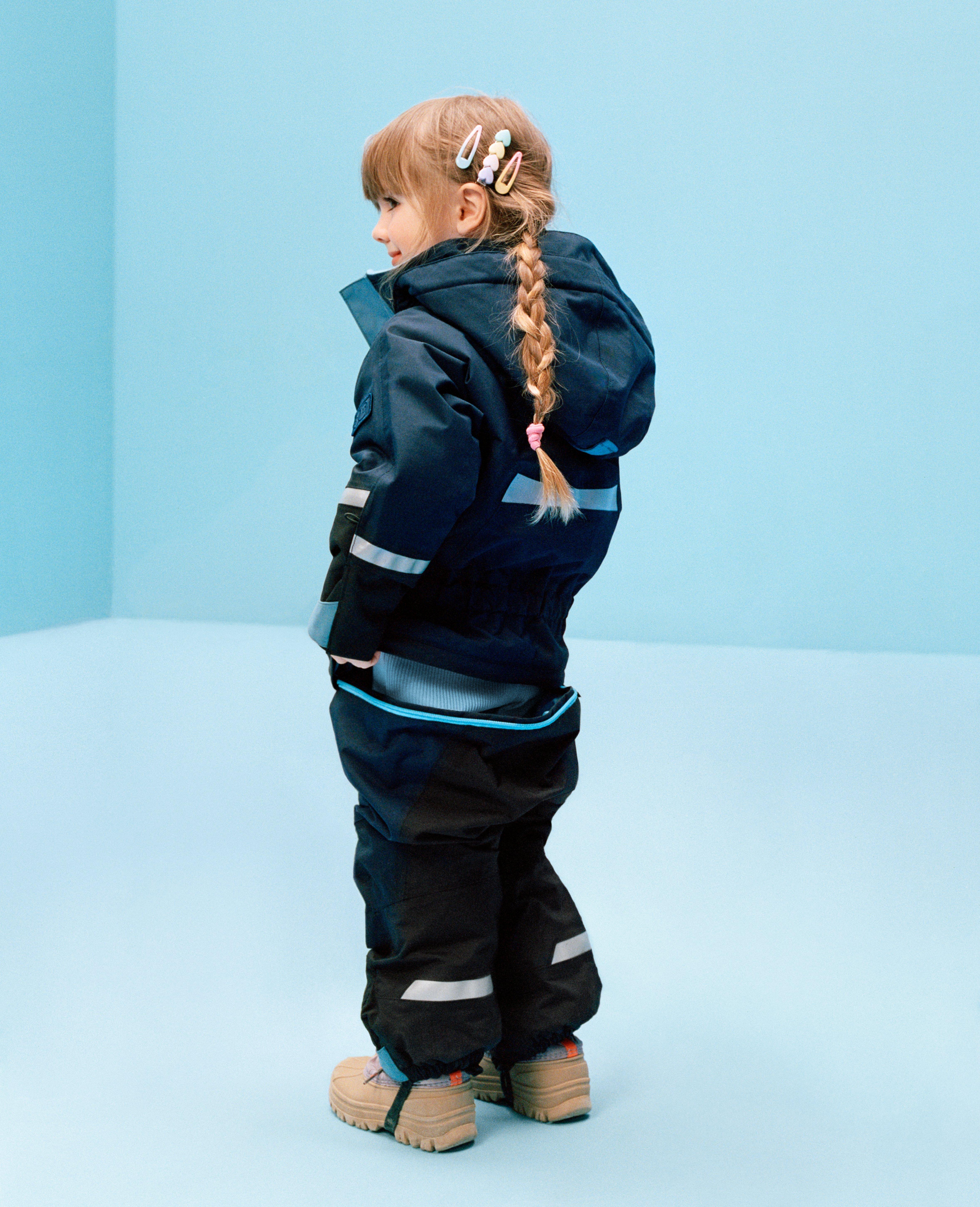 En flicka klädd i ytterkläder med drop seat-funktion