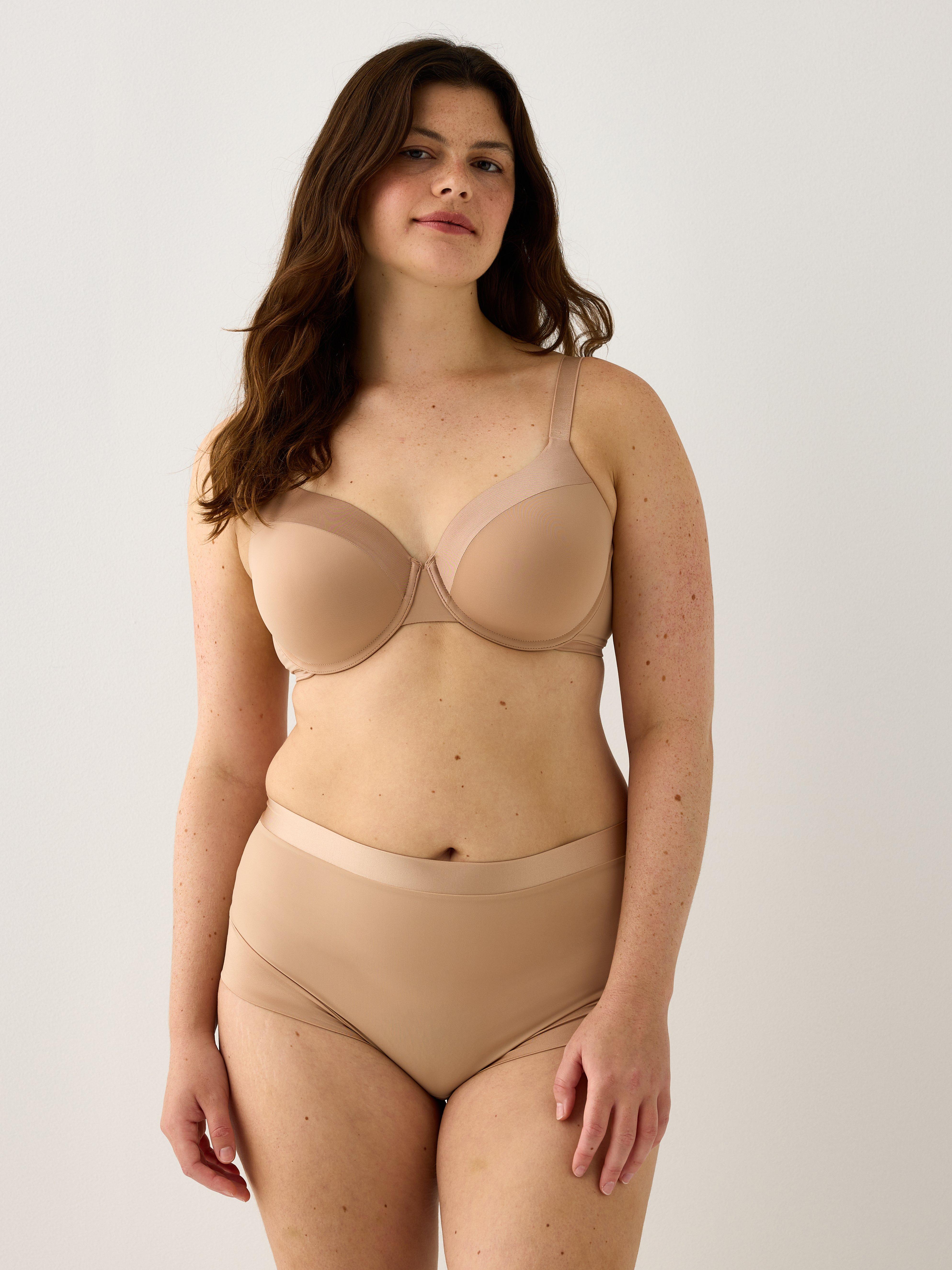 A woman in beige light support shaping briefs from Lindex.