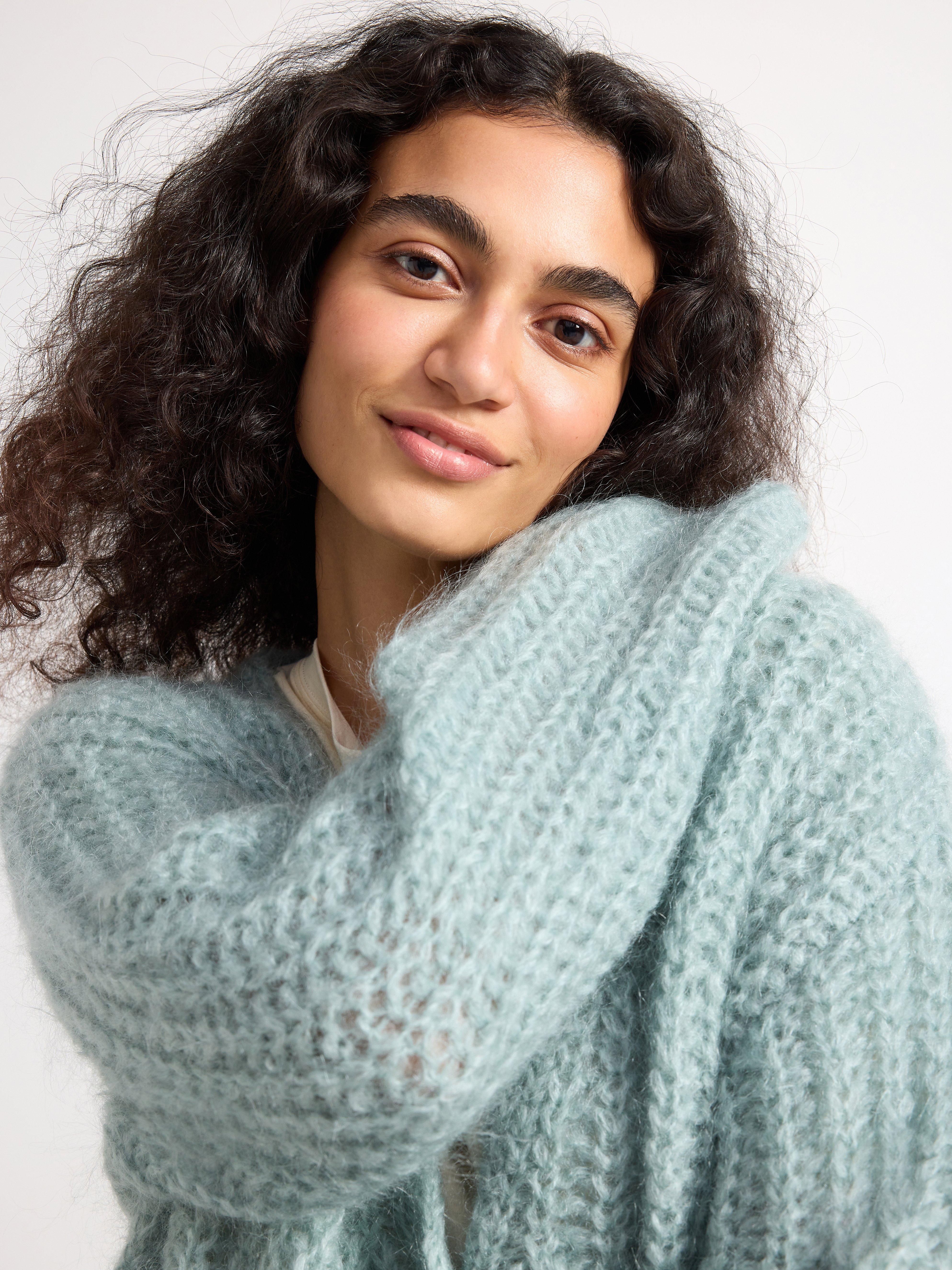 A woman in a turquoise knitted woolen cardigan.