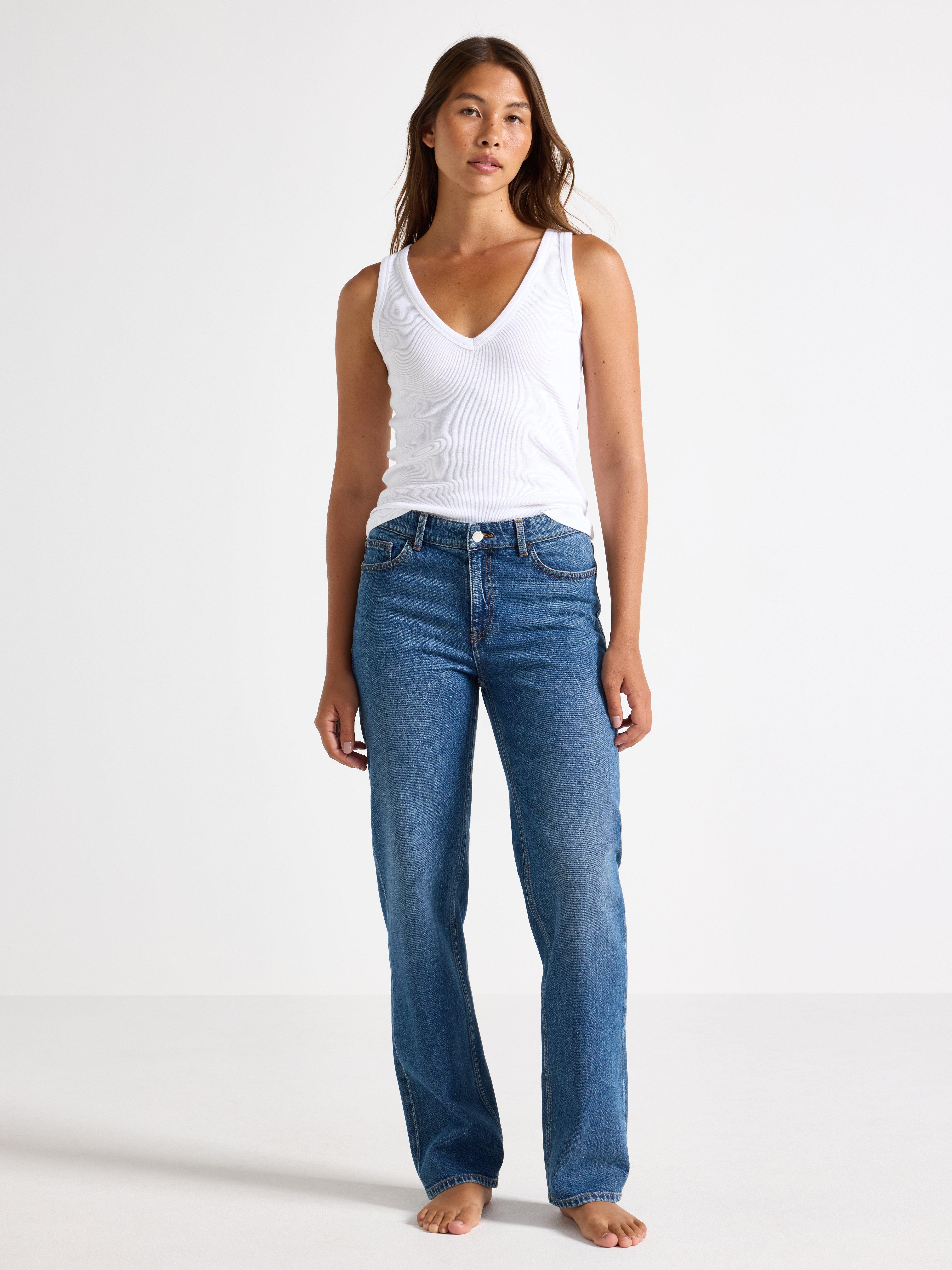A woman in a pair of straight blue jeans and a white t-shirt.
