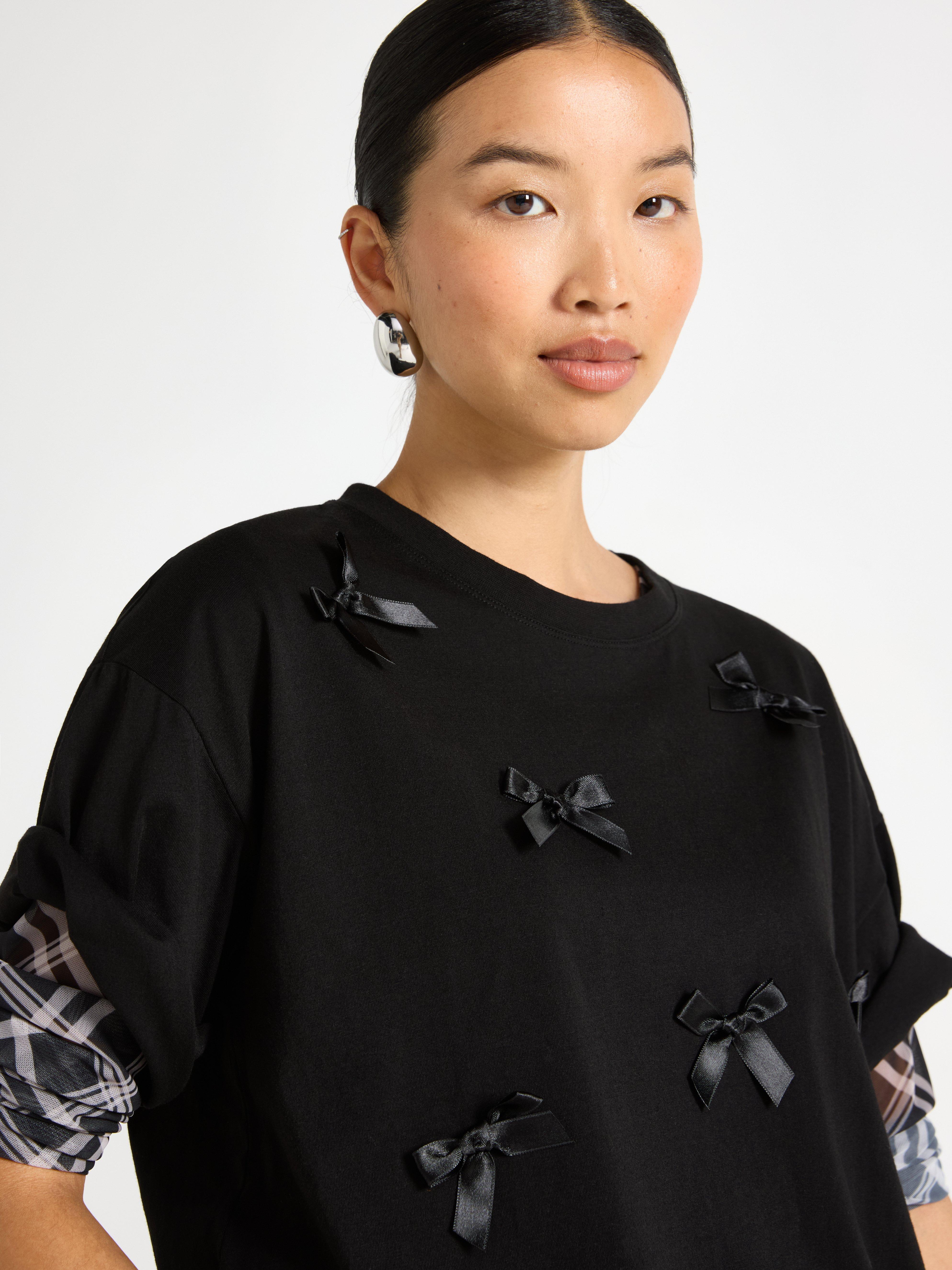 A woman wearing a black t-shirt with bows on it.