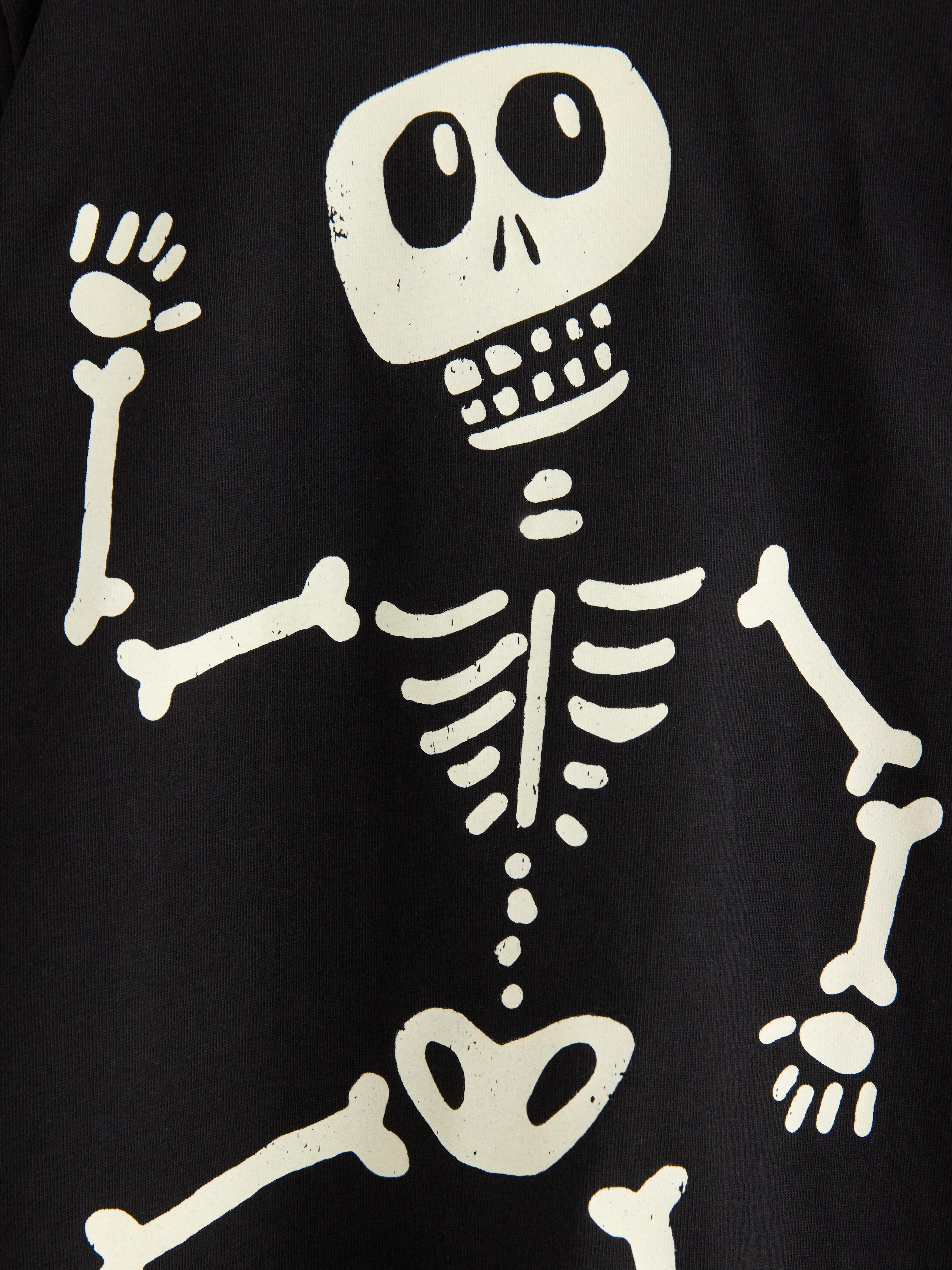 Detailní fotografie potisku kostry na černém svetru.