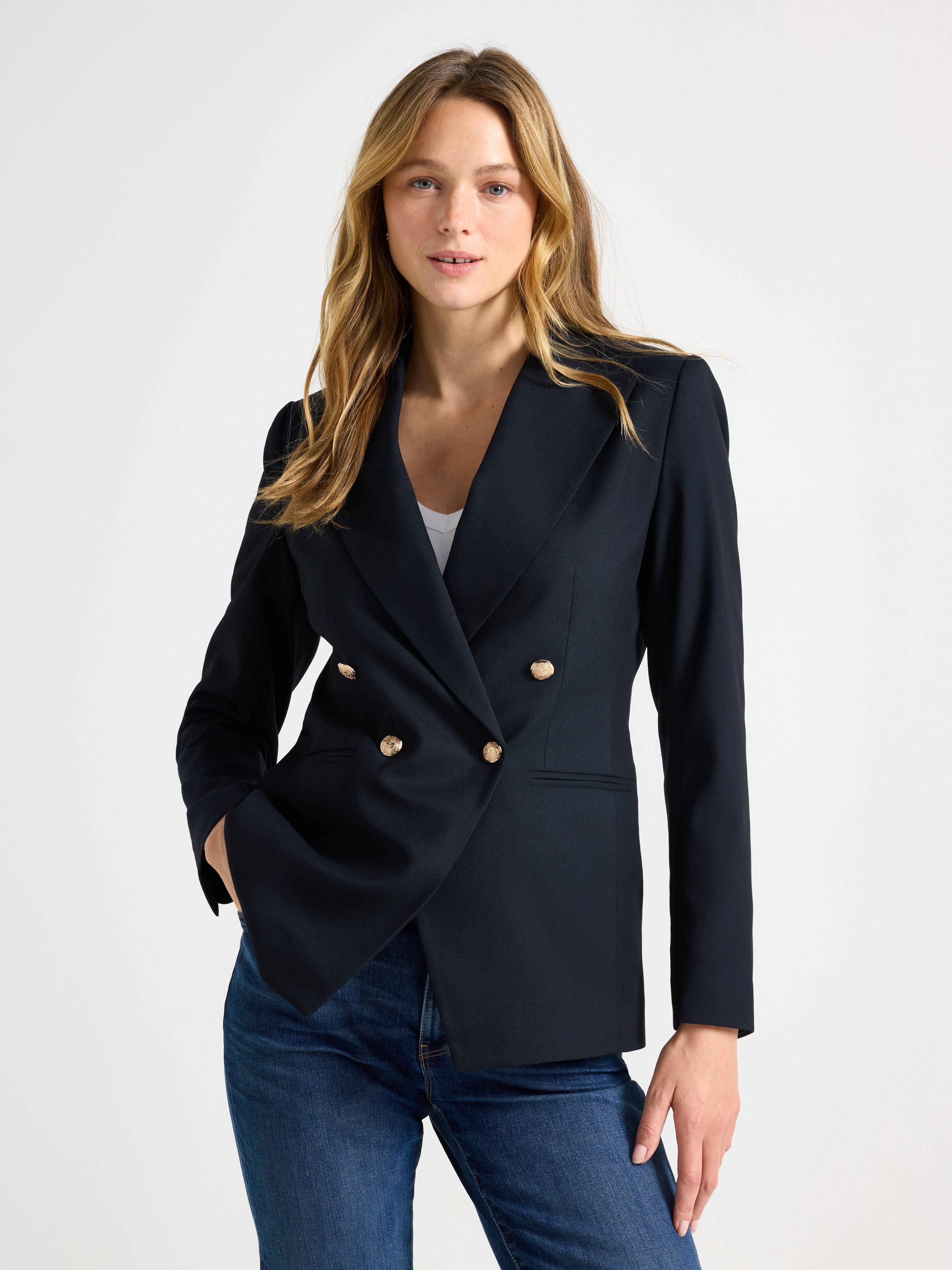 A close-up of a woman in a dark blue double-breasted jacket.
