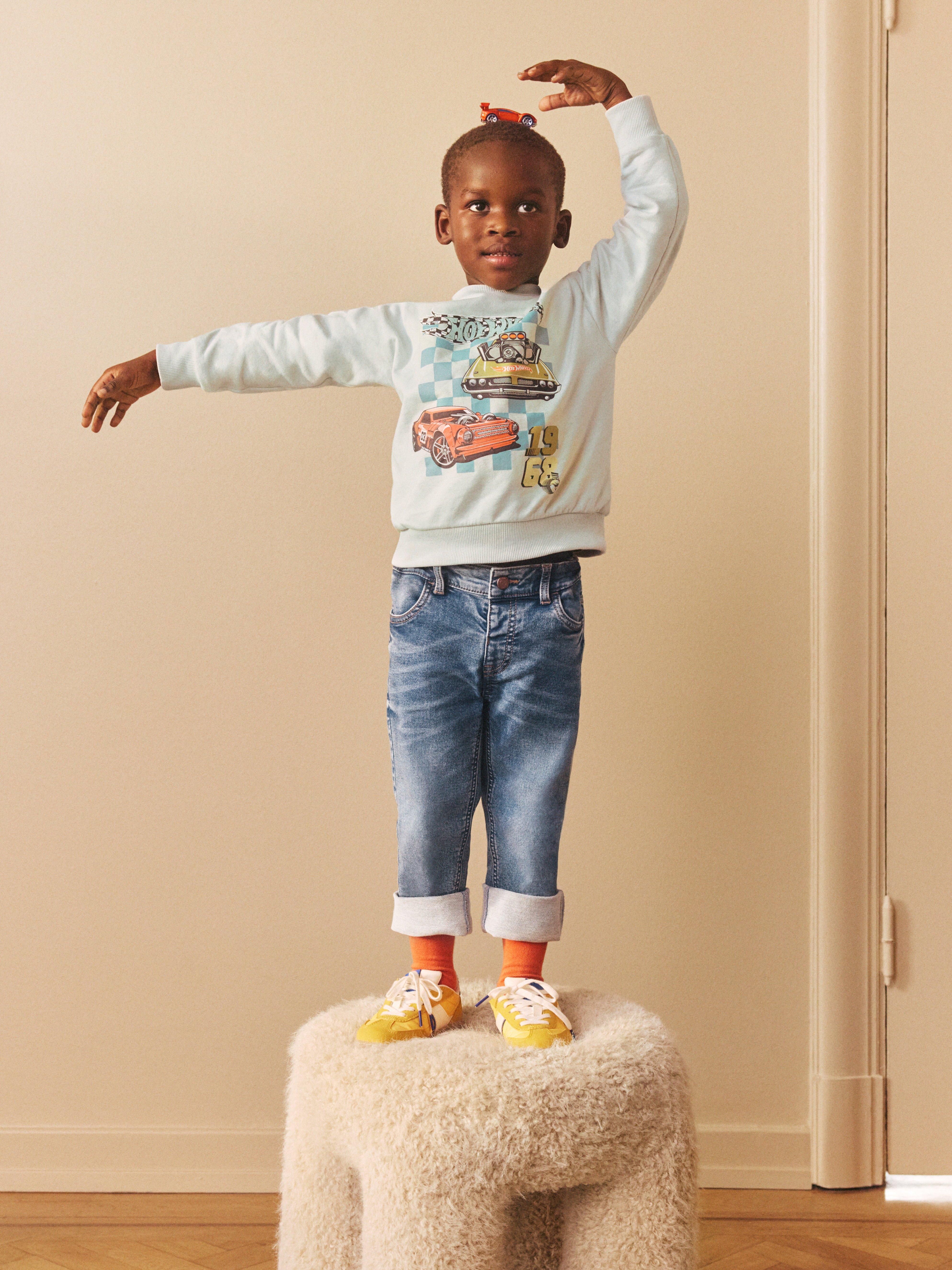 A small boy in a Hot wheels sweatshirt.