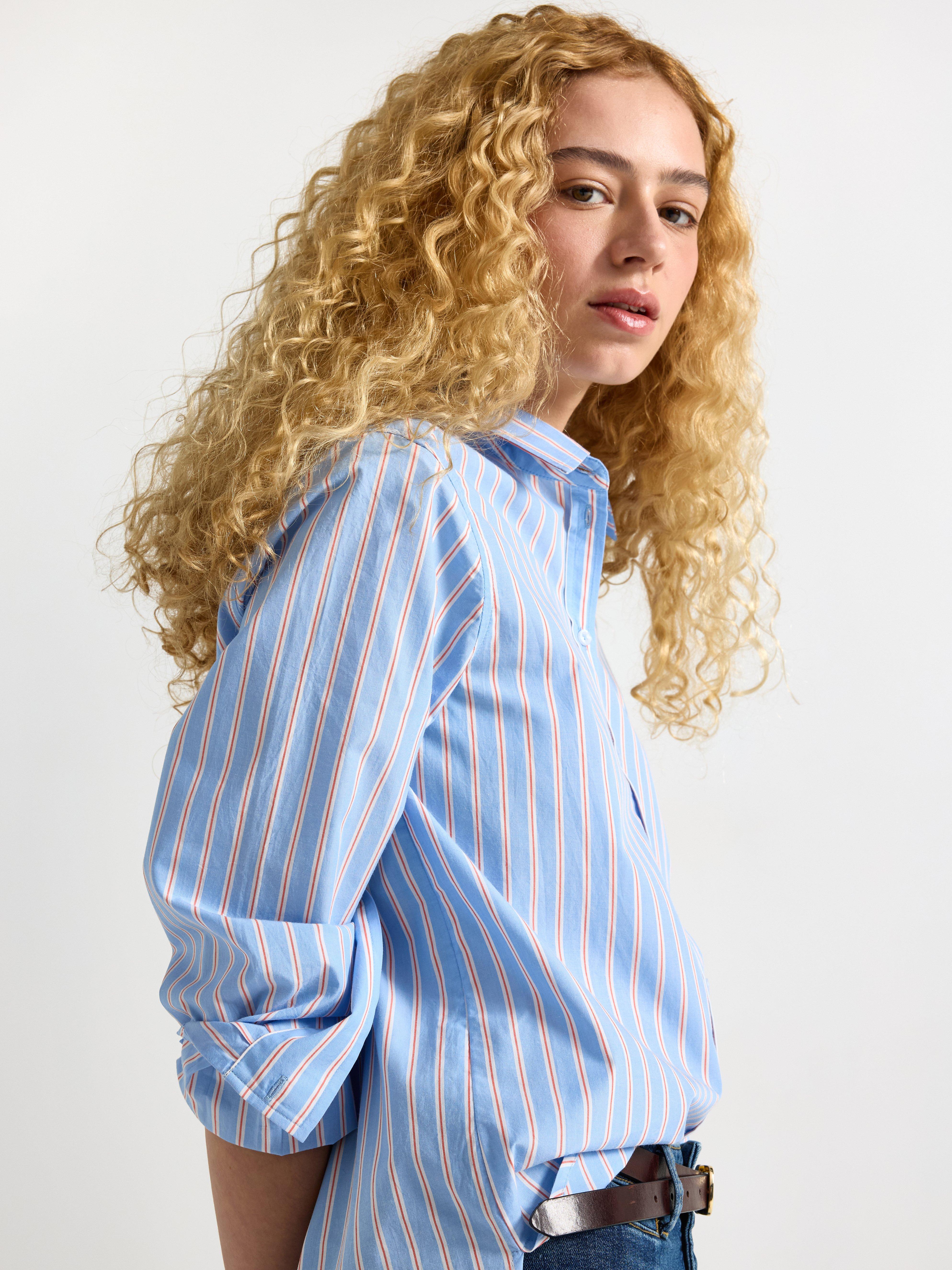 A close-up of a woman in an blue shirt with red and white stripes.