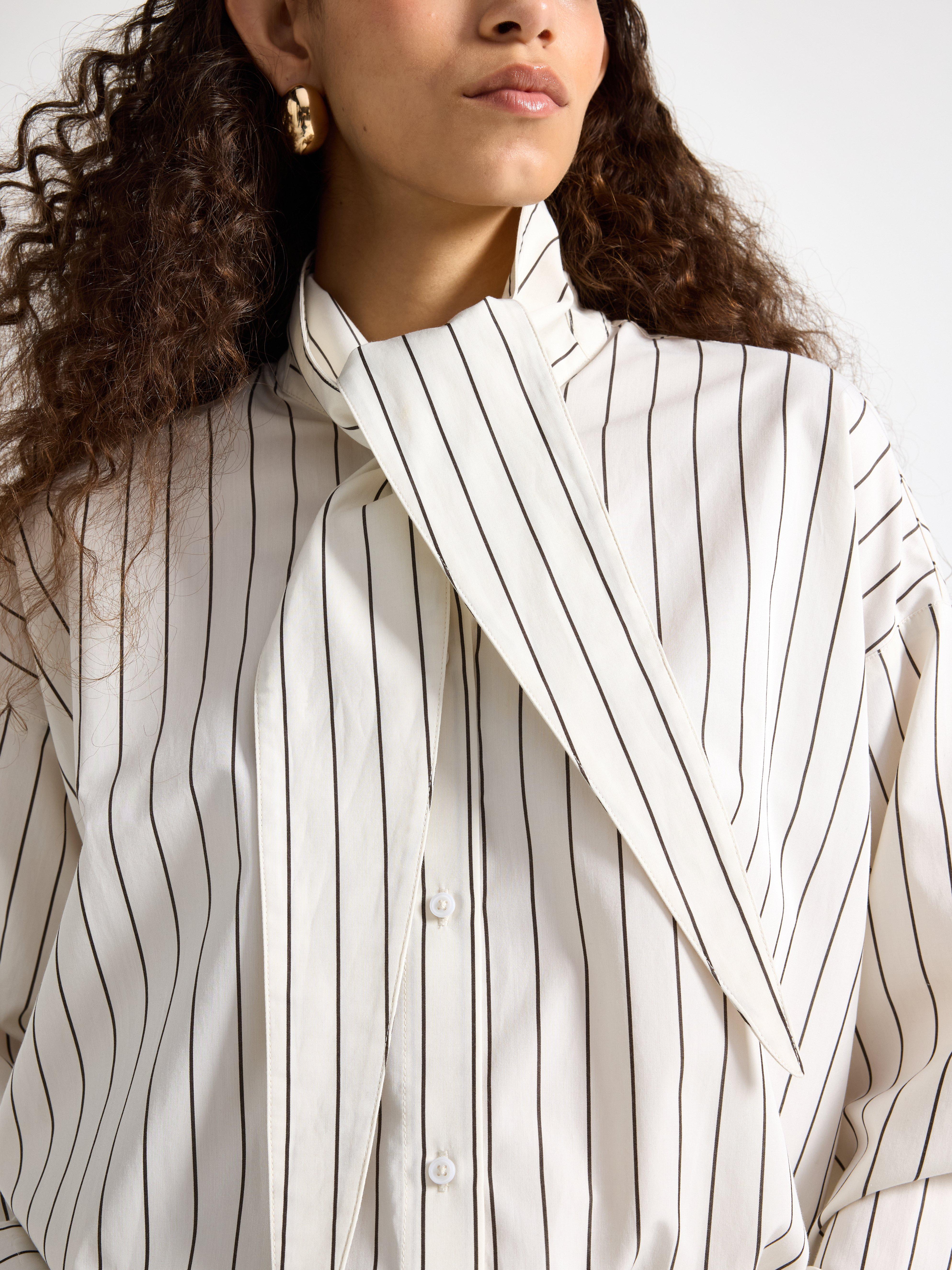 Close-up of a white and black striped shirt with a tie band at the neck.