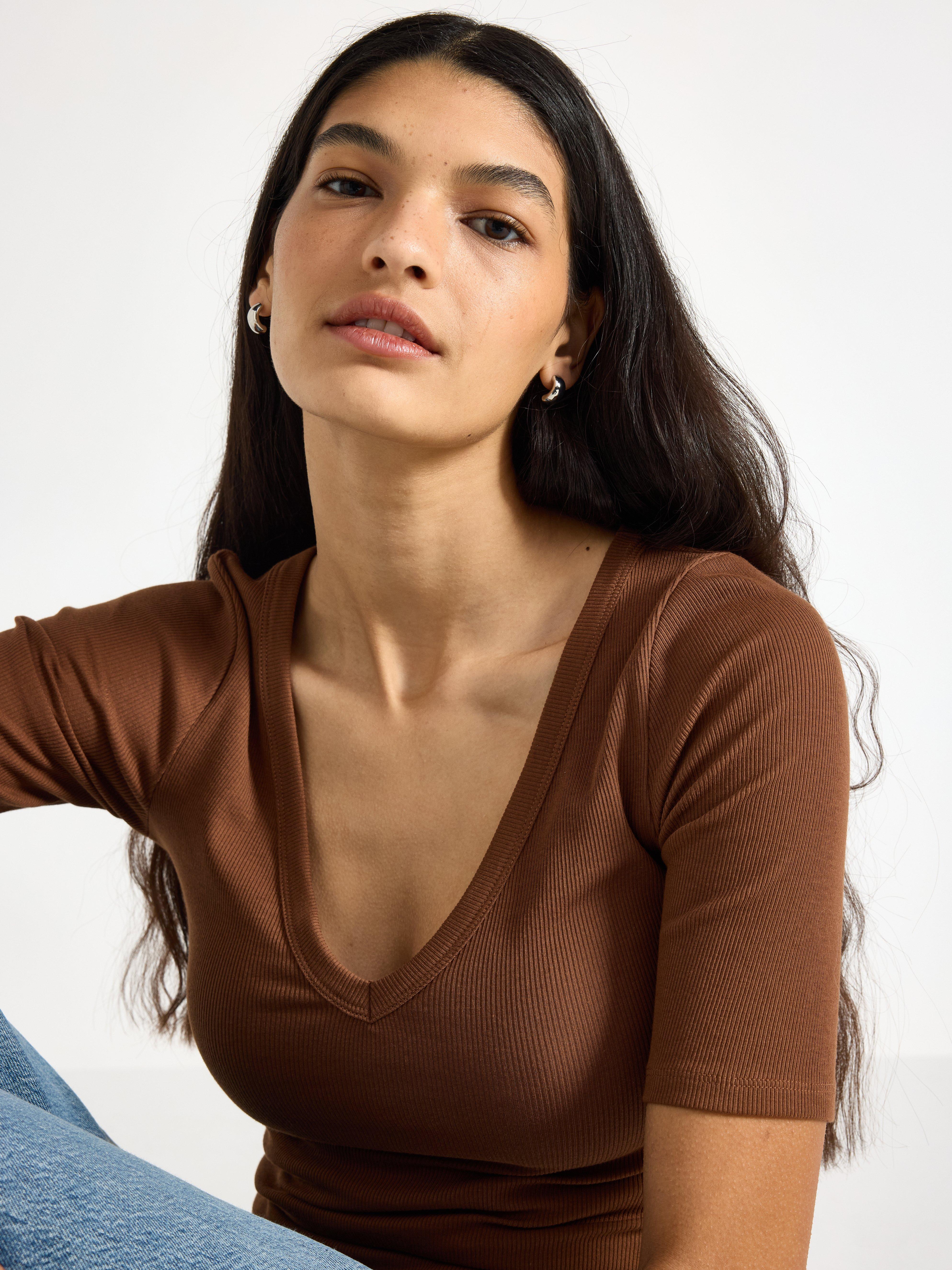 A close-up of a woman in a brown top.