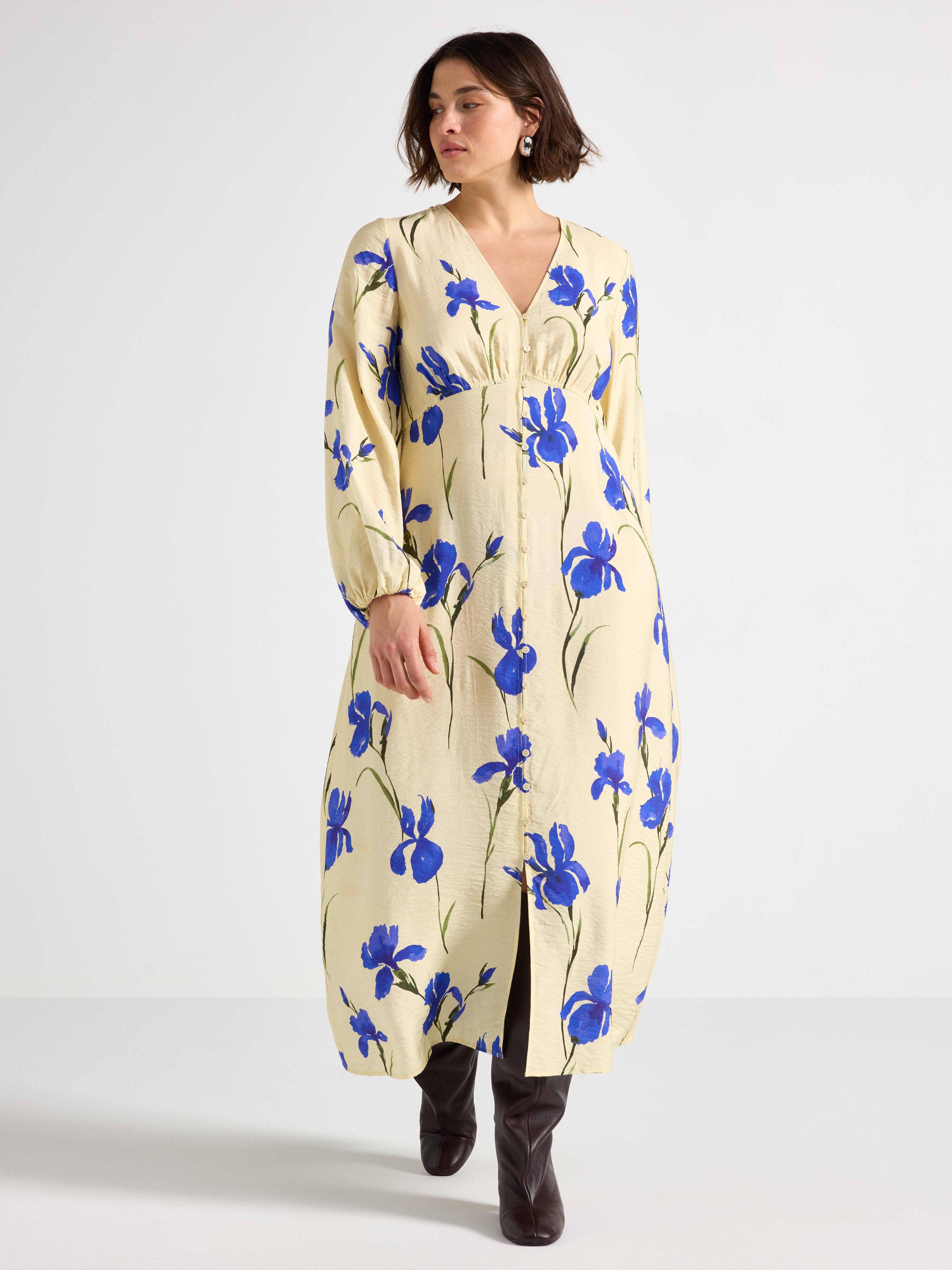 En kvinde i en gul kjole med blå blomster.