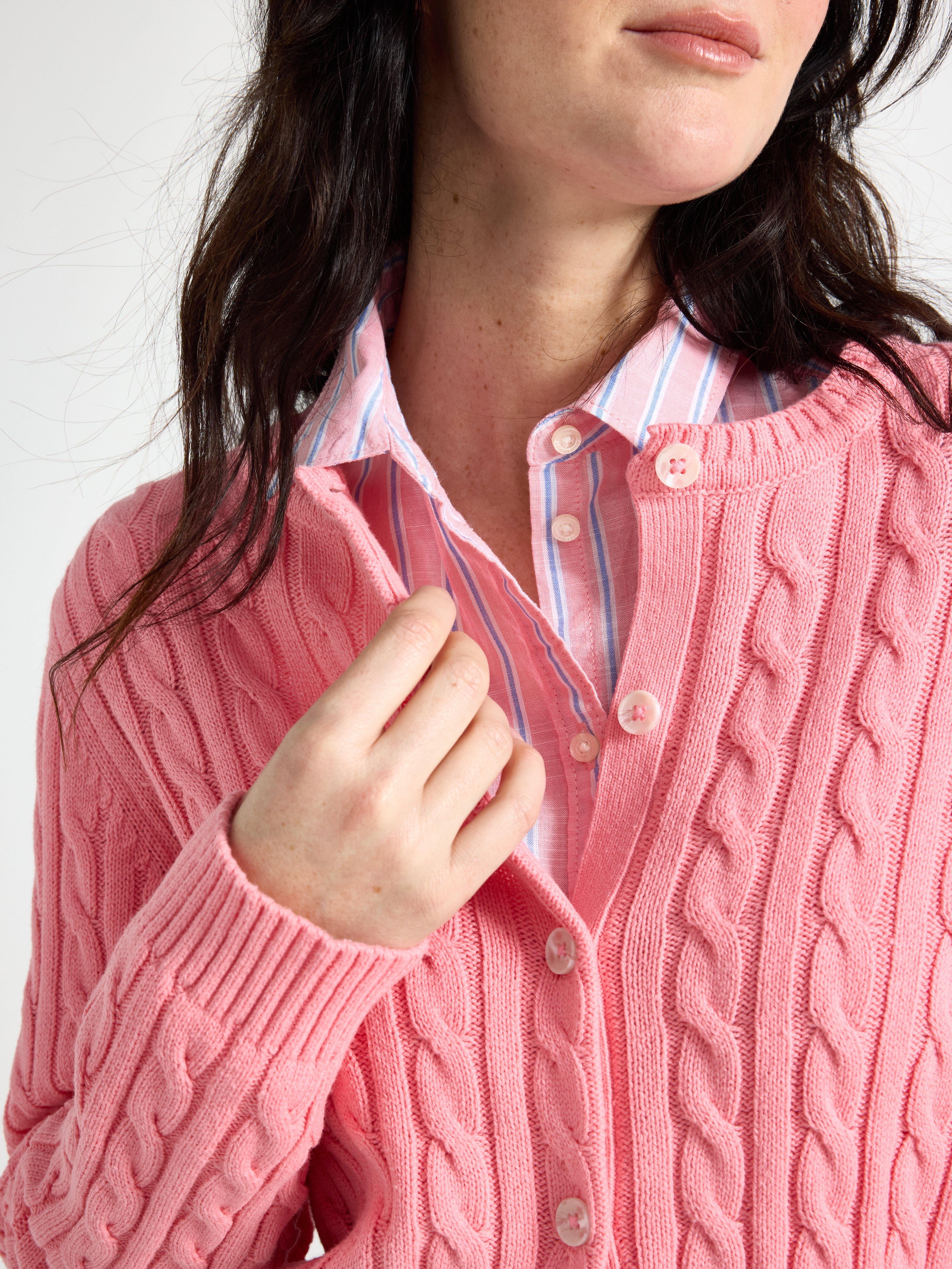 En närbild av en kvinna i en rosa kabelstickad kofta.