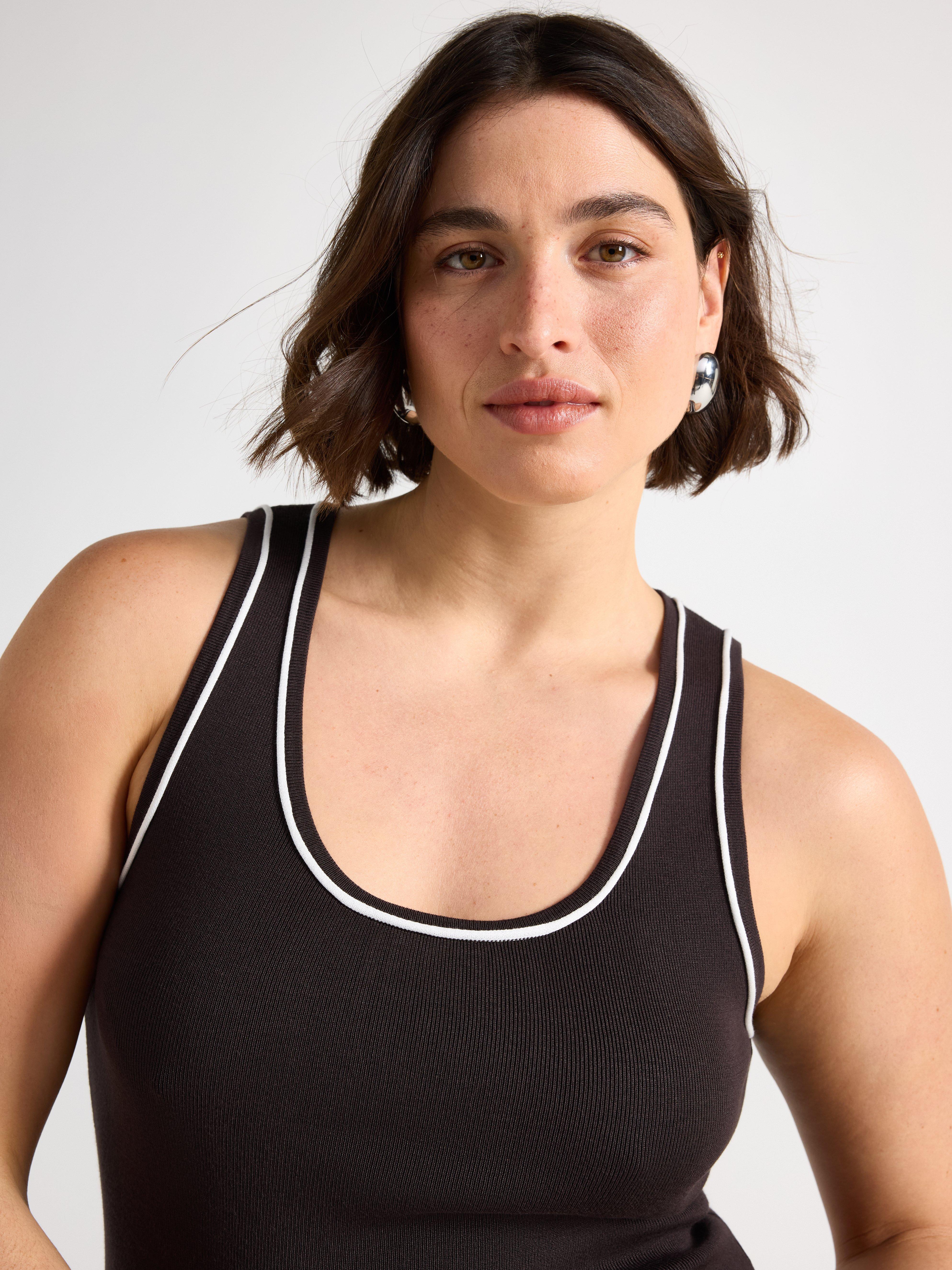  A woman wearing a brown fine-knit tank top.