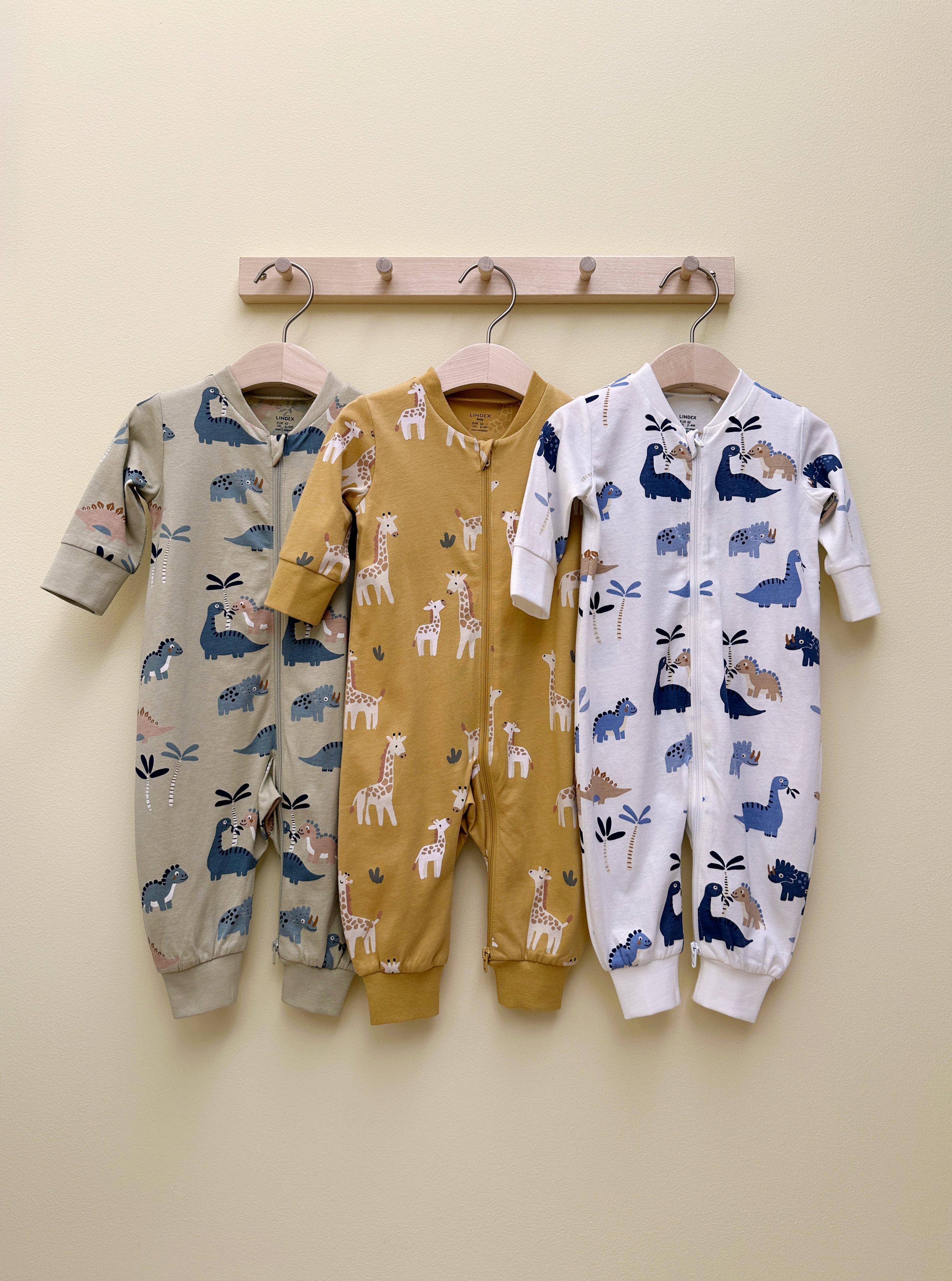  Several baby pajamas are hanging on a wooden rack.
