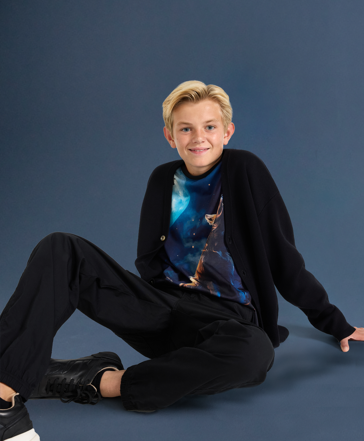 Chlapec sedí na podlaze. Má na sobě tričko s motivem Halloween.