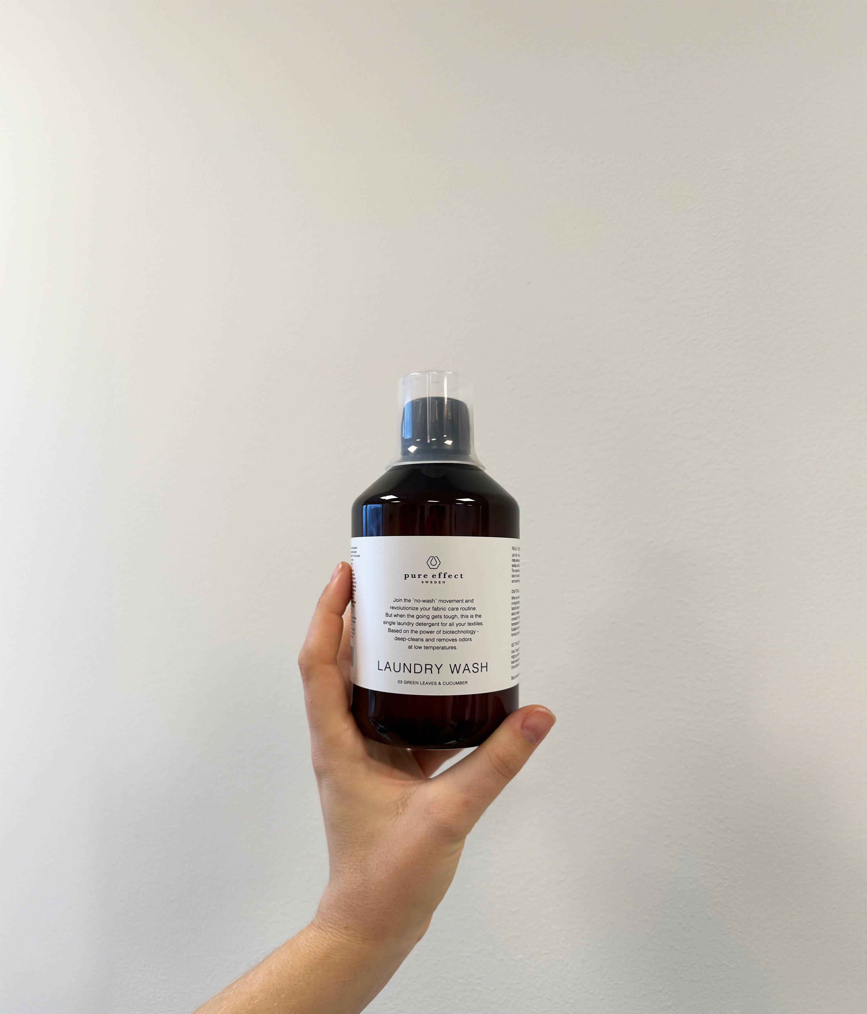  En hand som håller ett Pure Effect-tvättmedel.