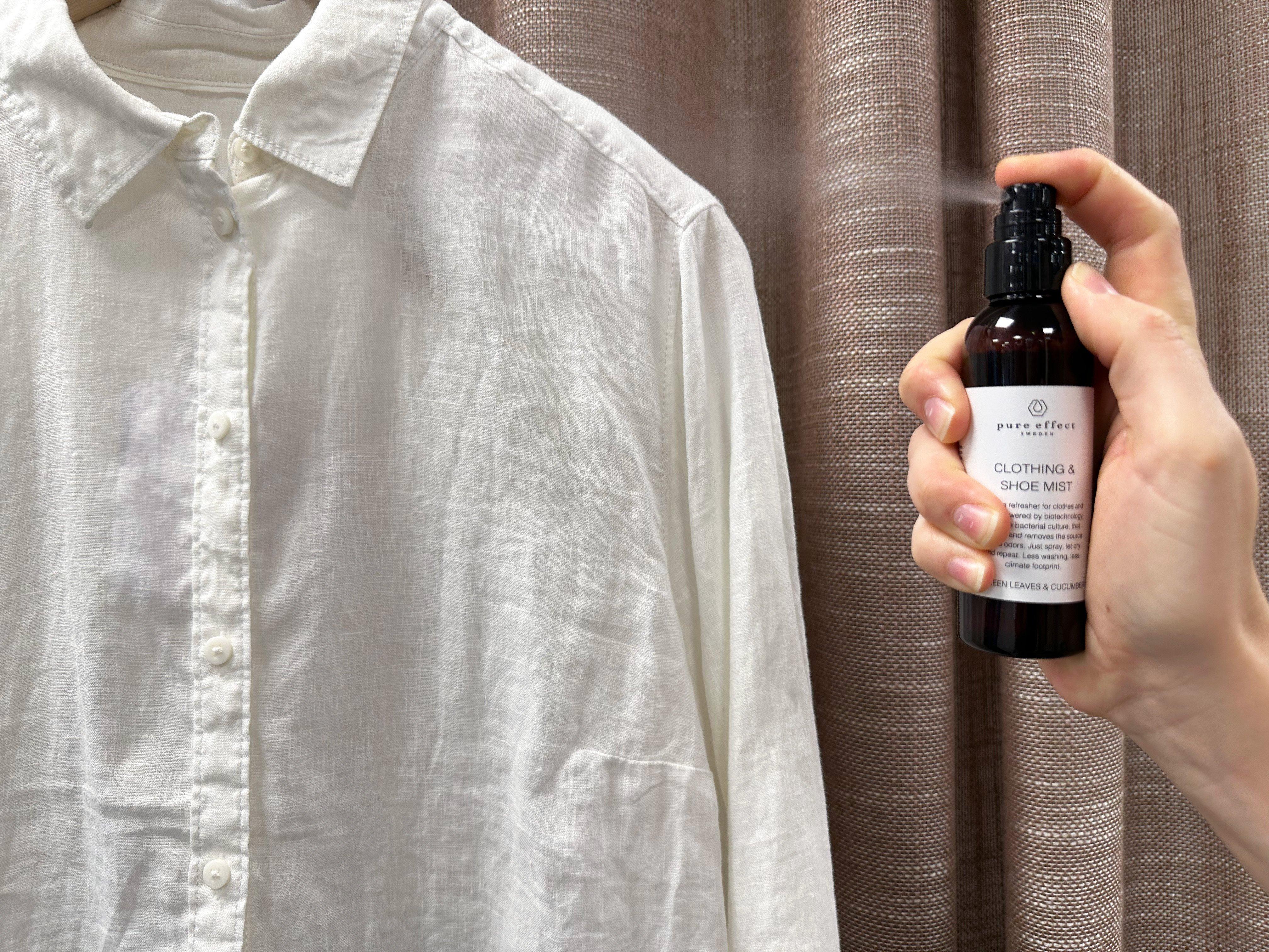 En hånd som sprayer Pure Effect på en hvit skjorte.
