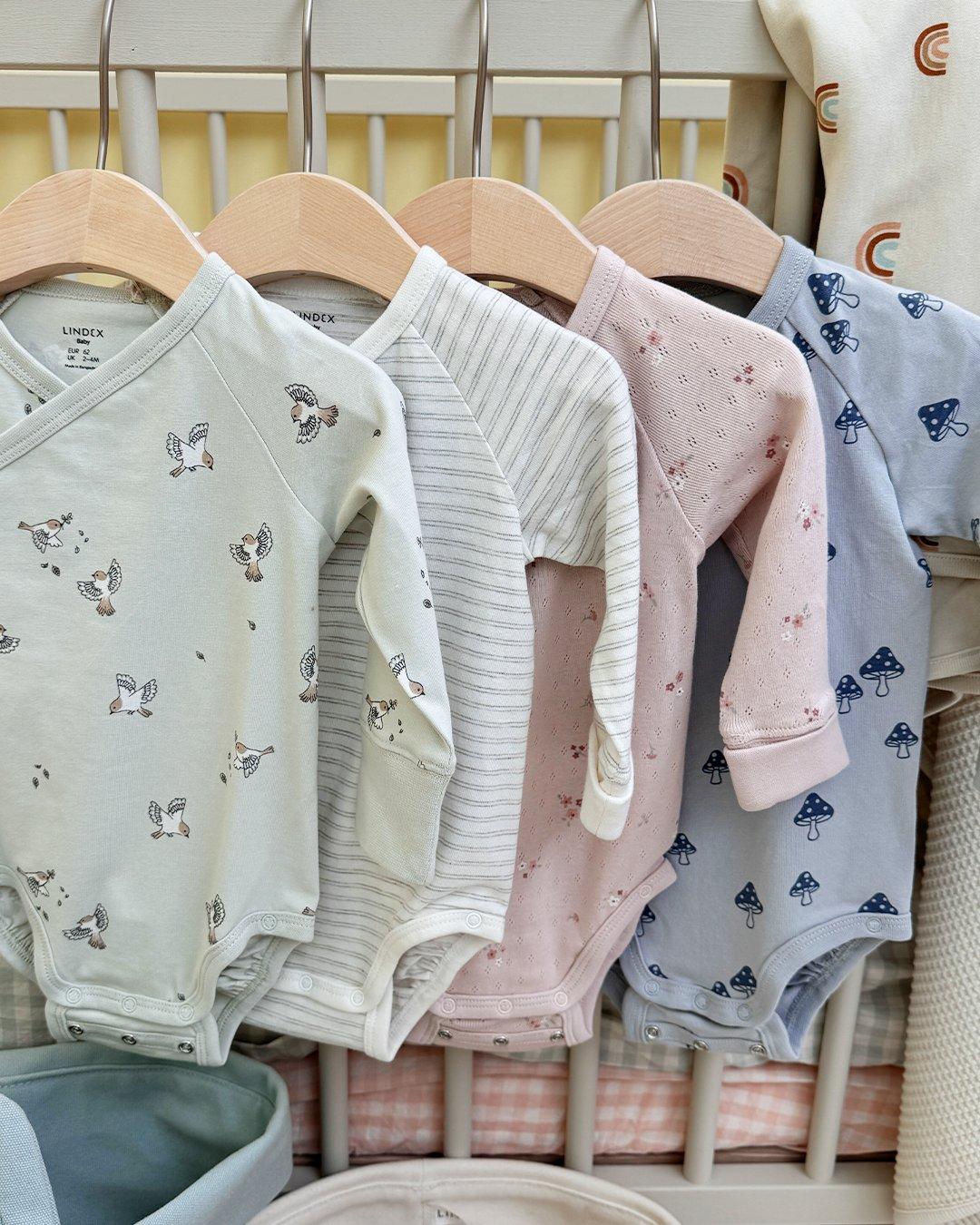 Several baby bodies from Lindex hanging on a clothes rack.