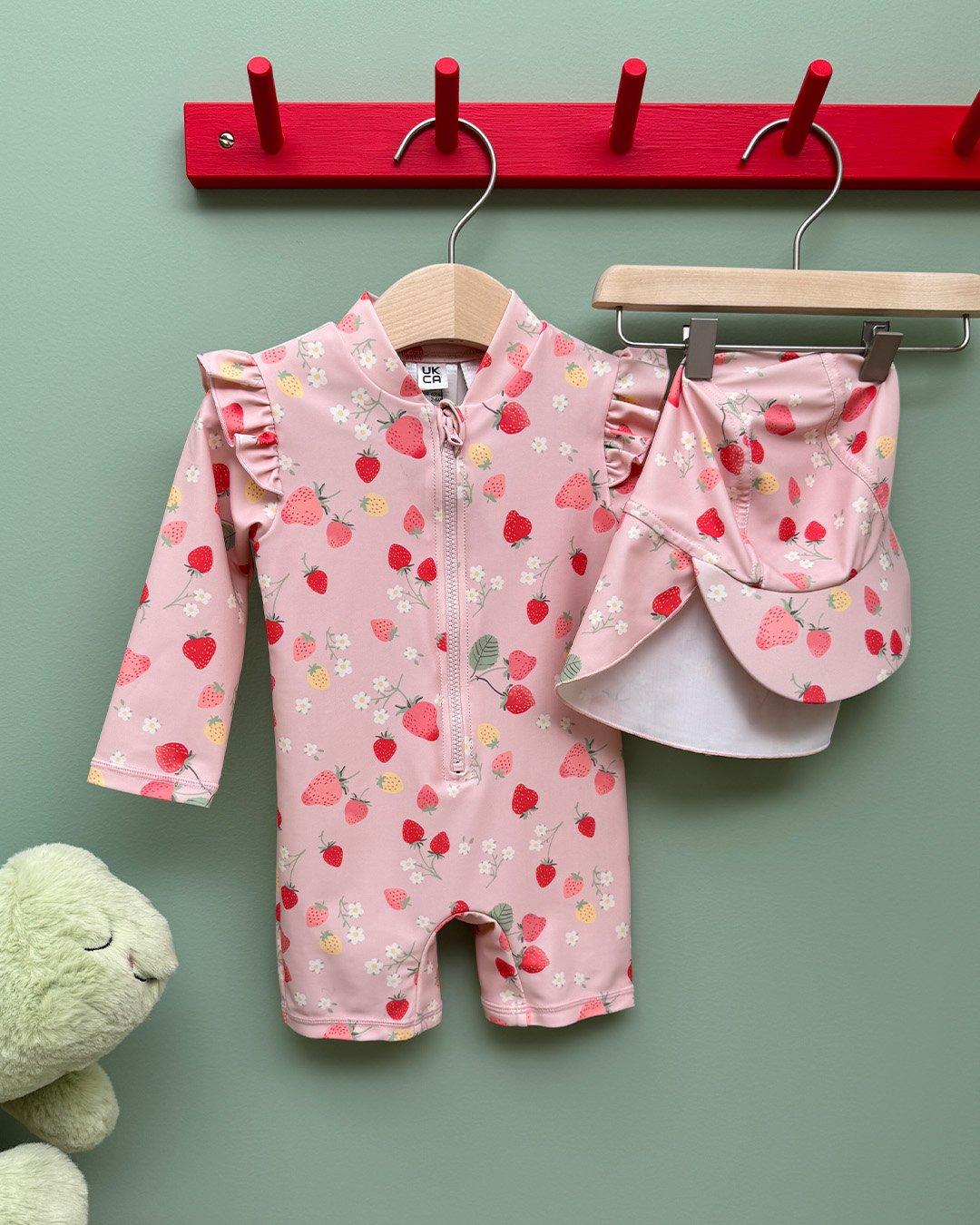 A close-up of a pink sun protection suit with strawberries.