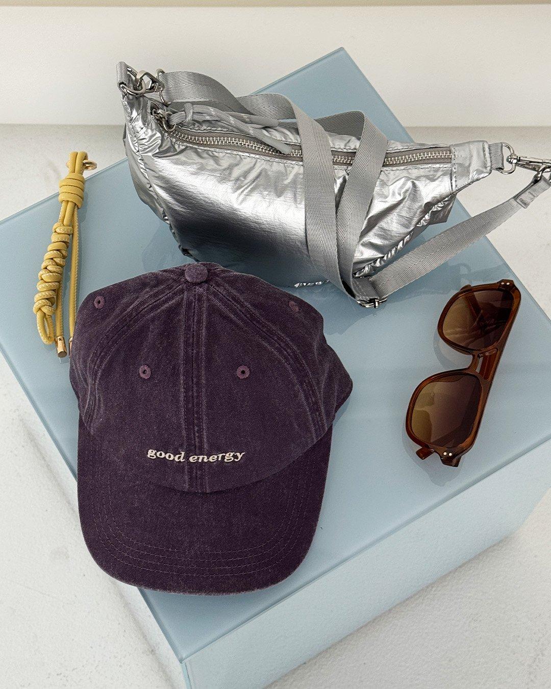 Čiapka, strieborná taška a pár slnečných okuliarov ležia na stole.