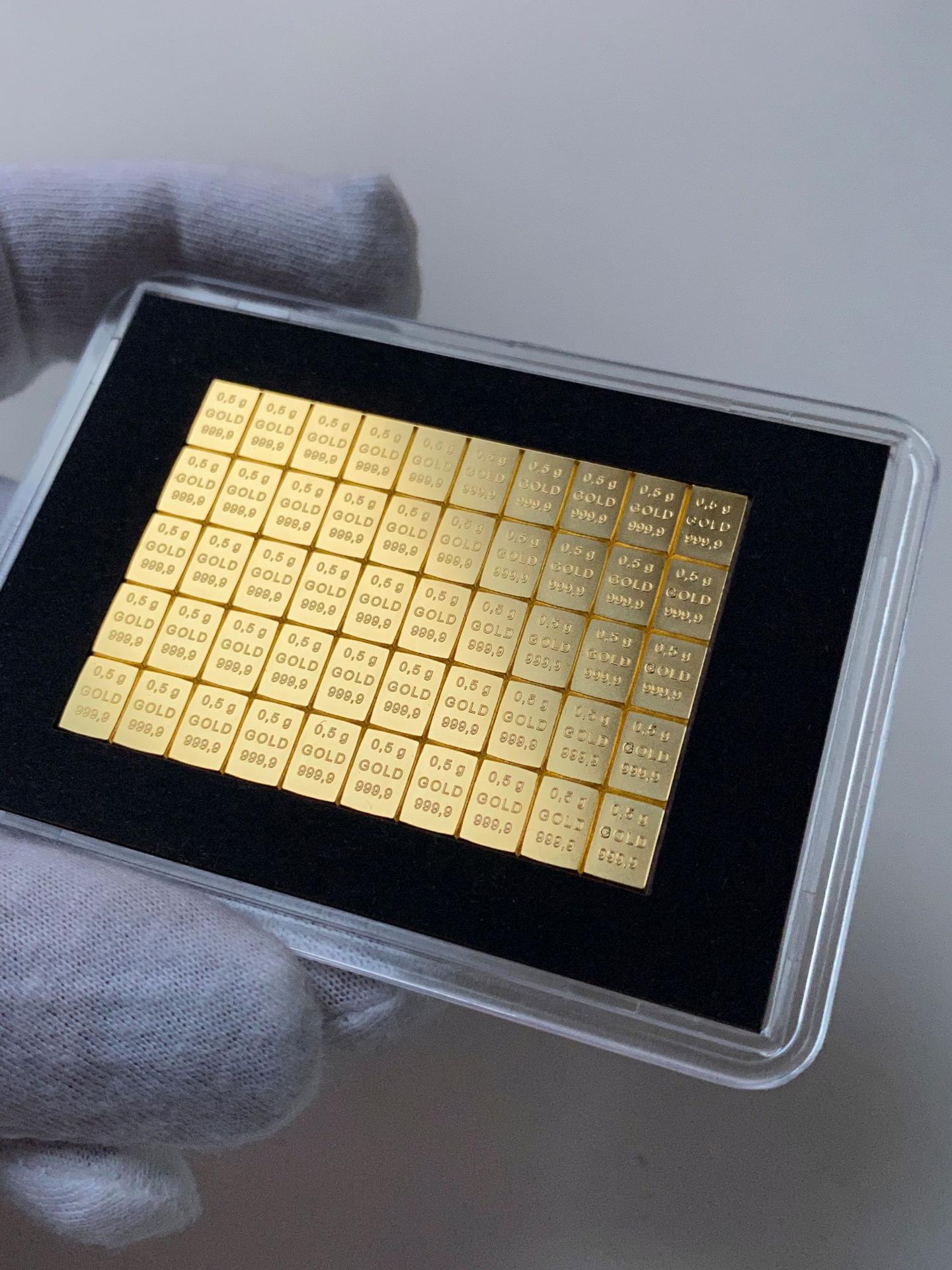 Goldbarren-Tafel aus kleineren 0,5g Feingoldbarren in schwarzer Schatulle, gehalten mit Handschuh.