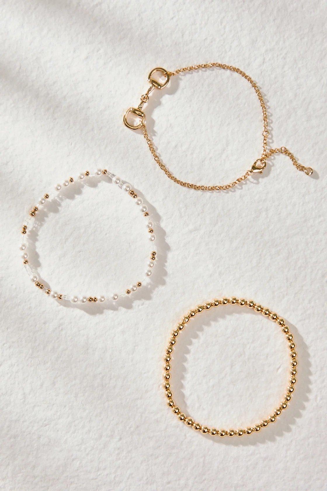 Three 18k gold-plated bracelets: pearl, horse bit, and polished gold circle designs