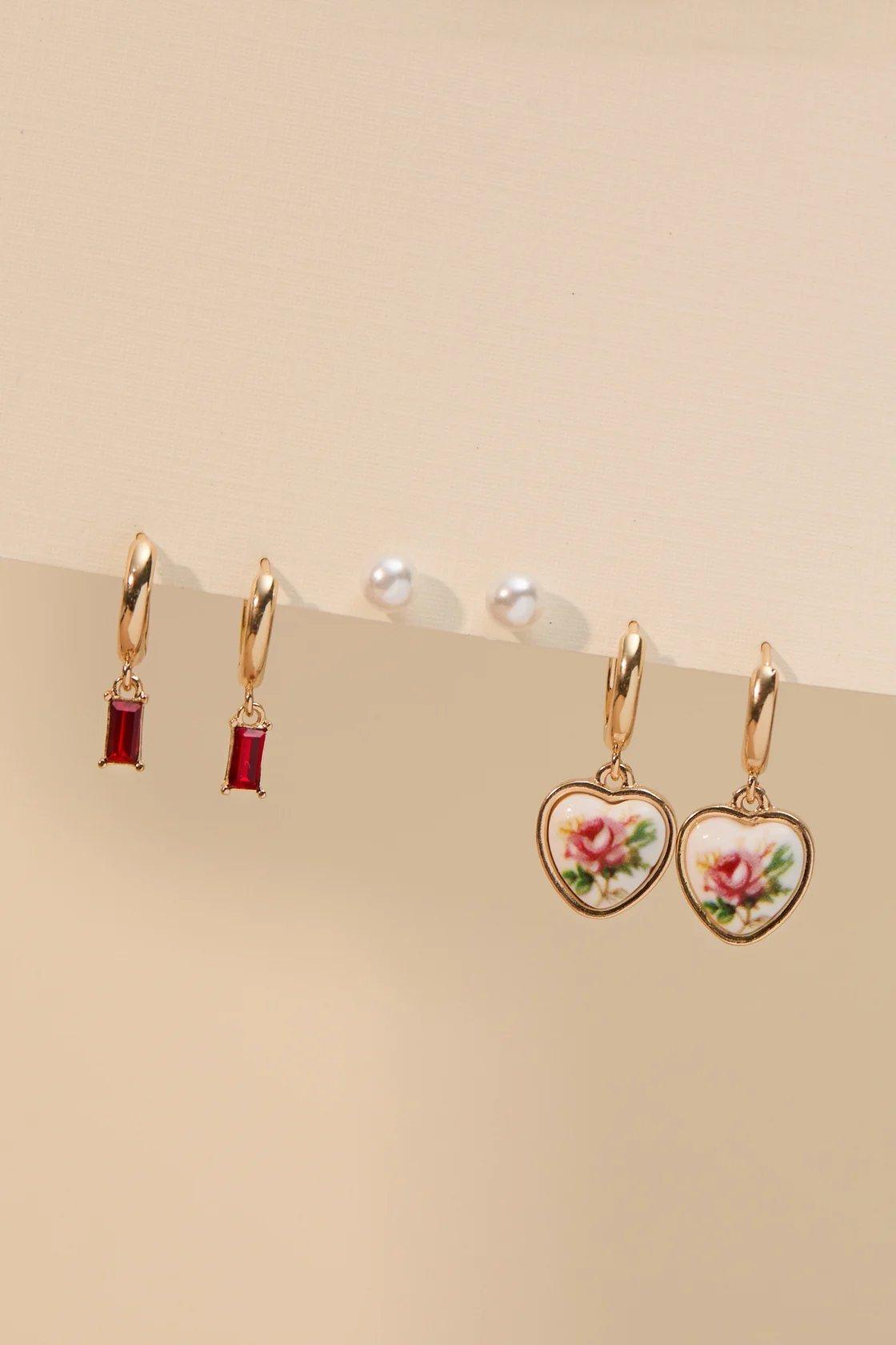 three set of earrings including pearls, heart pendant, and red stone earrings