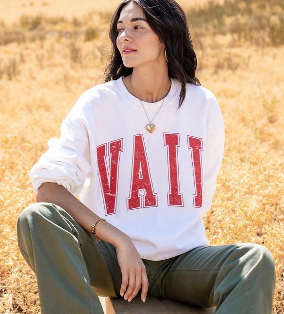 Woman wearing a white sweatshirt with word Vail in red