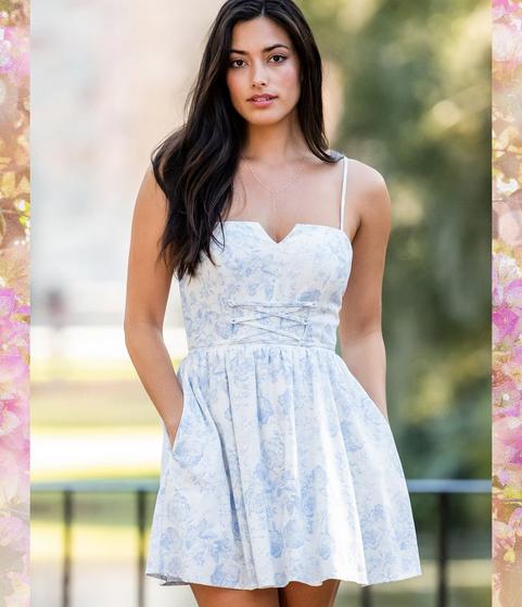 Woman wearing a sleeveless blue and white floral mini dress with a corset waistband