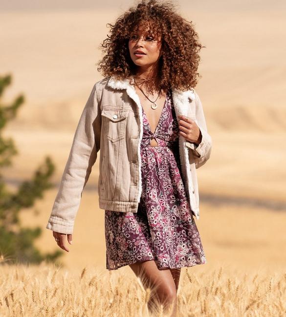 Woman wearing a floral mini dress with tan corduroy jacket