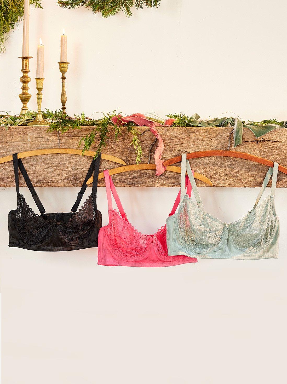 Various colored lace bralettes hung across a mantle