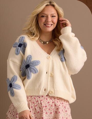 woman wearing an ivory cardigan with blue 3d flowers
