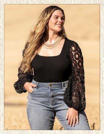 Woman wearing a black long sleeve top with crochet sleeves