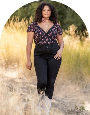 Woman wearing black high waisted skinny jeans and a black and purple floral top