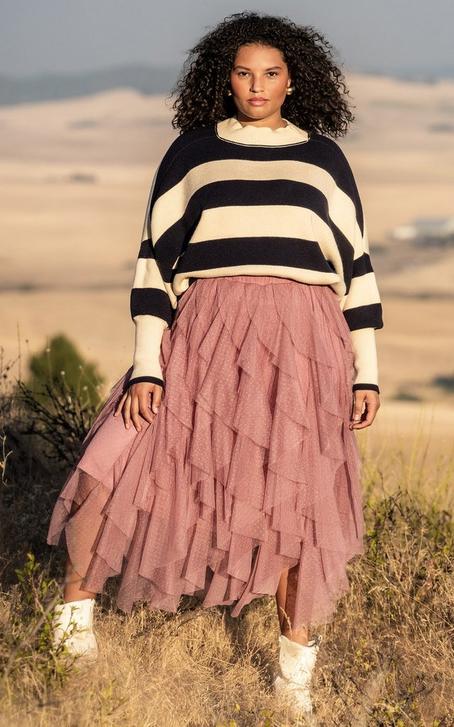 Woman wearing a navy blue stripped sweater and pink tierd tulle maxi skirt