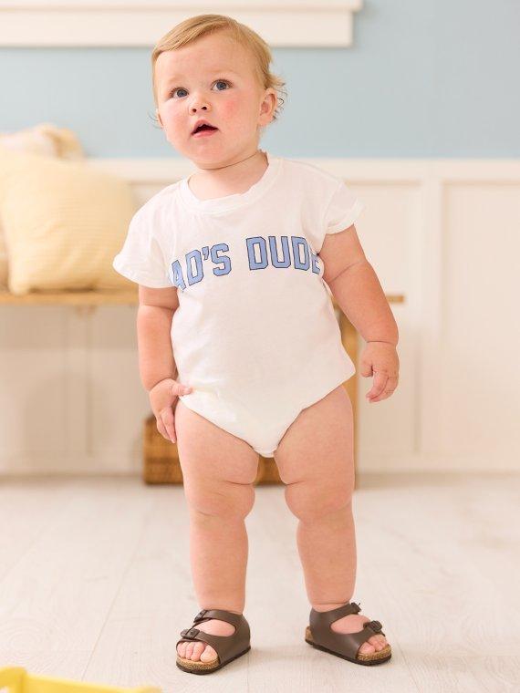Baby boy wearing a onsie with "Dad's Dude" written on the front